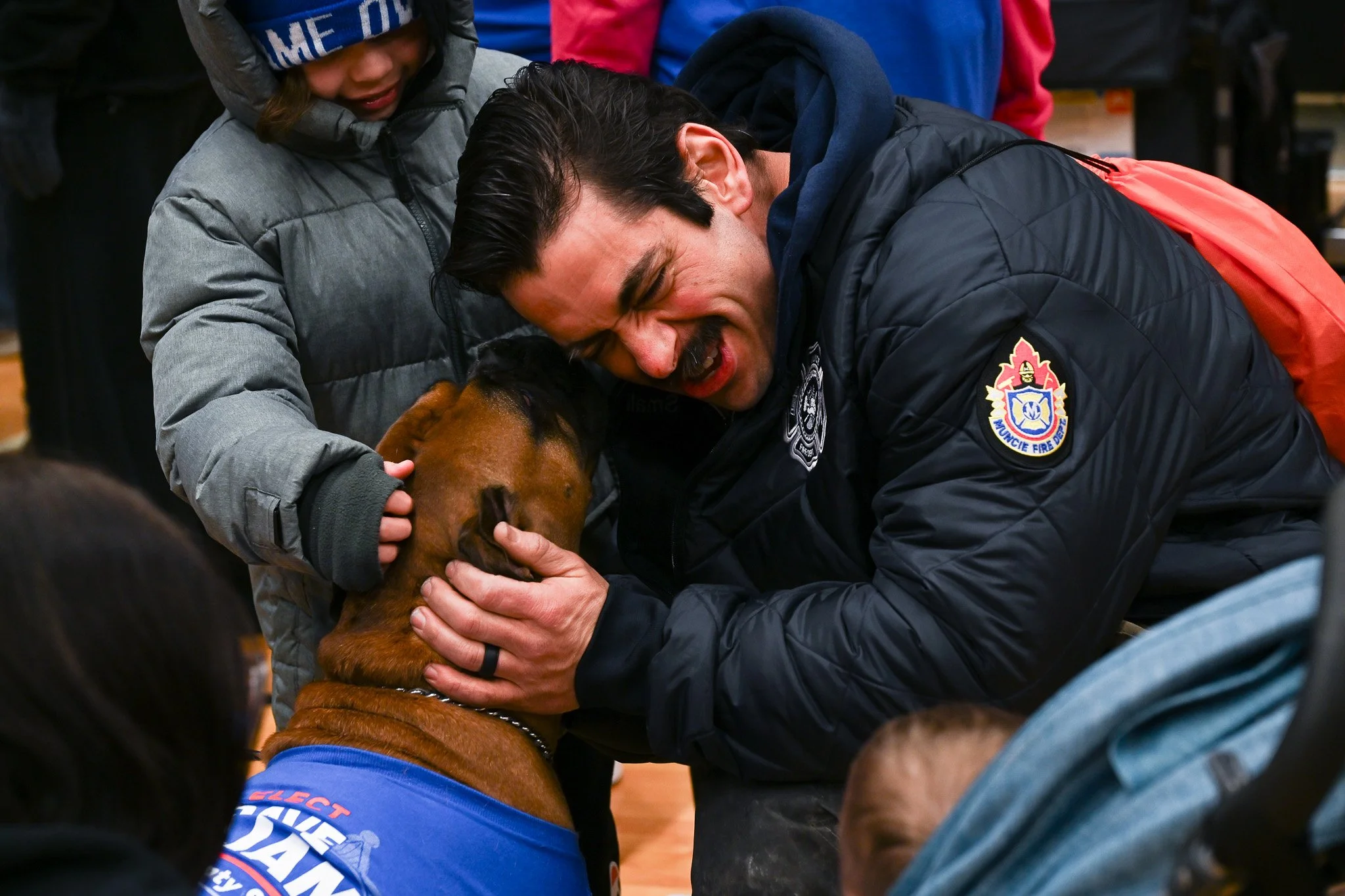 A firefighter from the Muncie Fire Department is licked by a dog during the Muncie Mission Walk a Mile in My Shoes event Feb. 21 in Muncie, Indiana. 