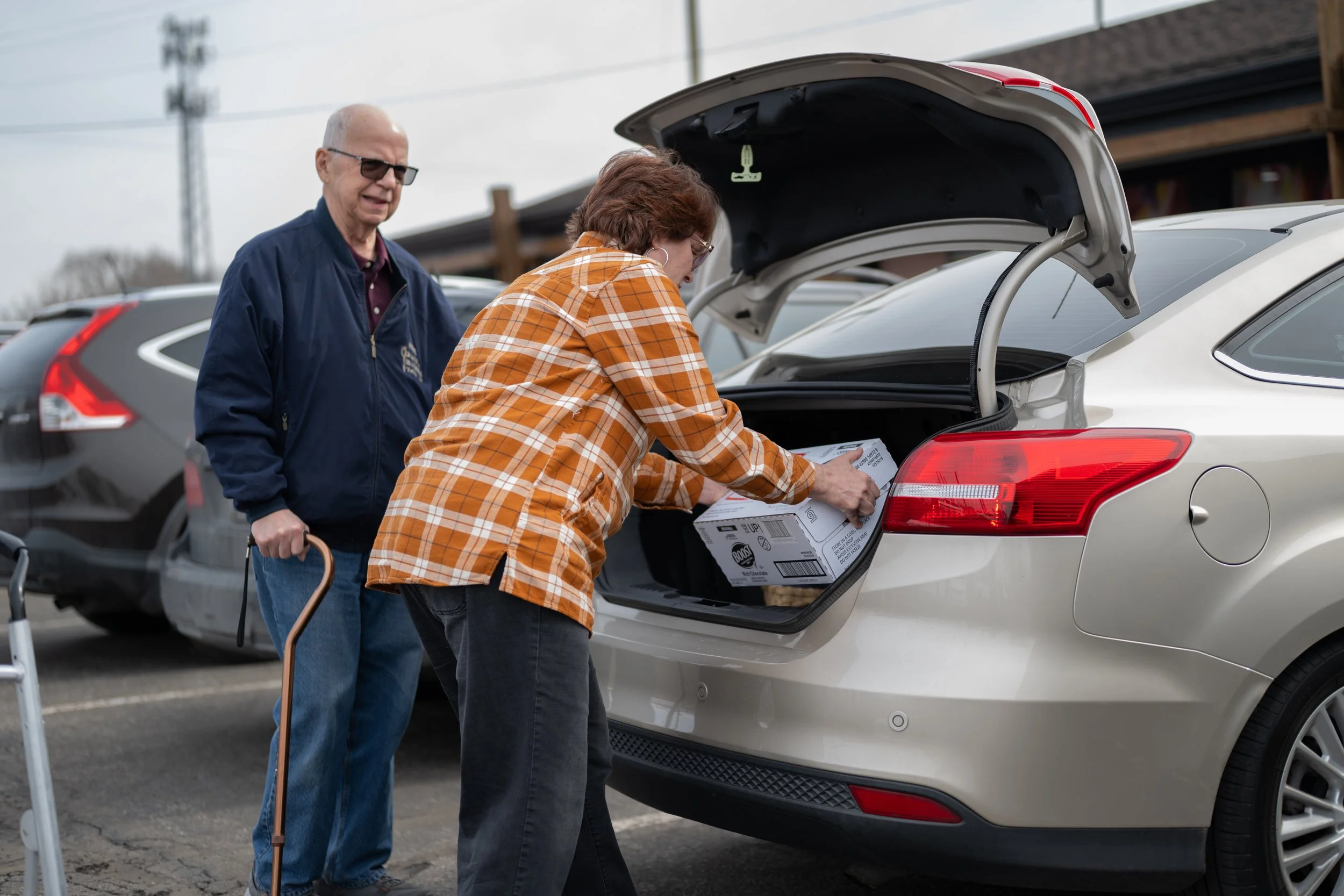 Rebecca Owen, right, assists Michal Newton in loading supplement Boost drinks into his vehicle Feb. 17 at the Muncie Little Red Door Office. Newton was diagnosed with esophageal cancer and uses the Boost drinks to receive nutrients when it is difficu