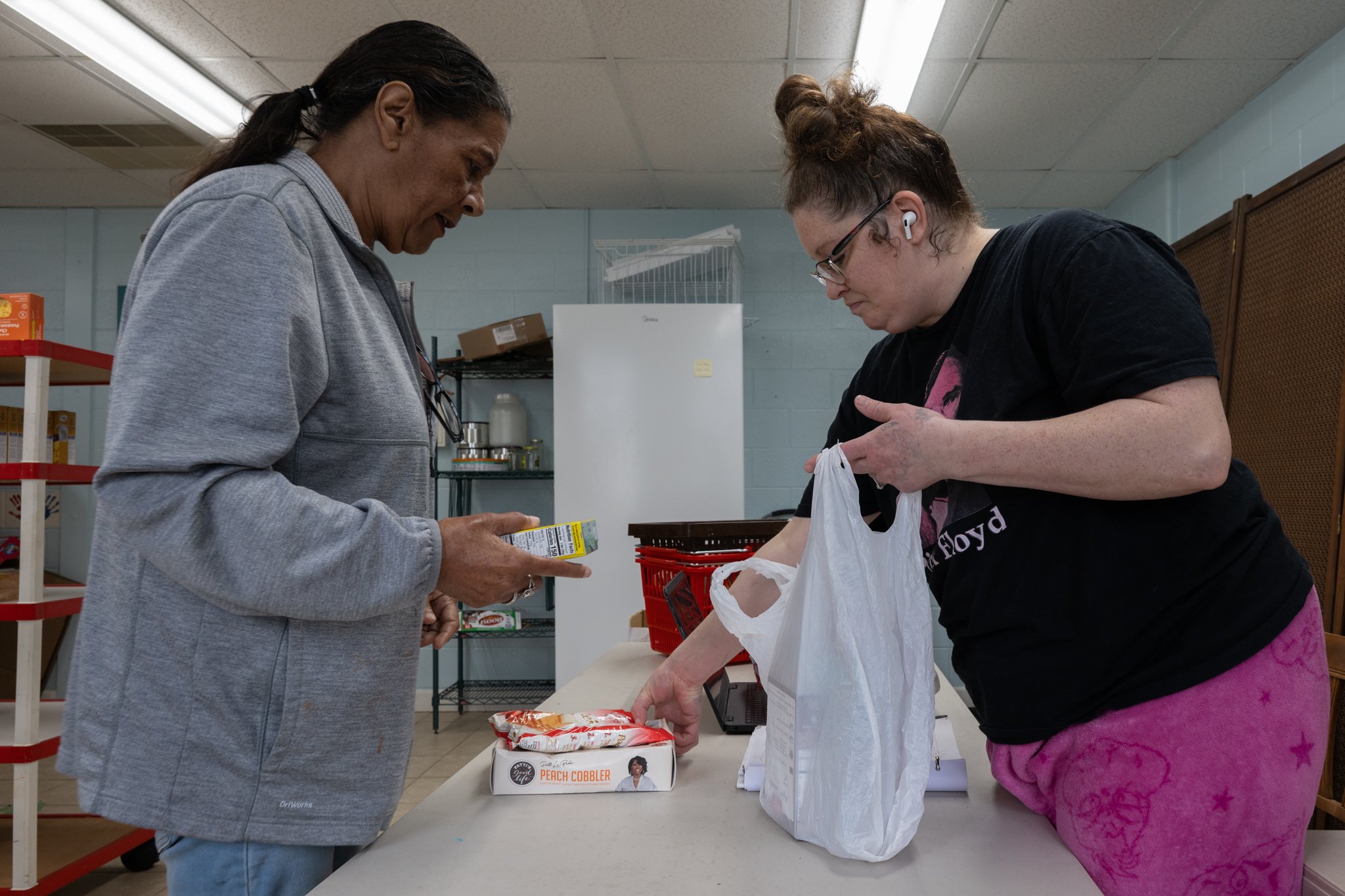 Tammy Beck, right, assists a guest of the Recovery Cafe Muncie with loading her groceries from the cafe’s food bank April 4 in Muncie, Indiana. The cafe hosts a food bank for guests that is open every Saturday. It’s arranged to resemble a standard gr