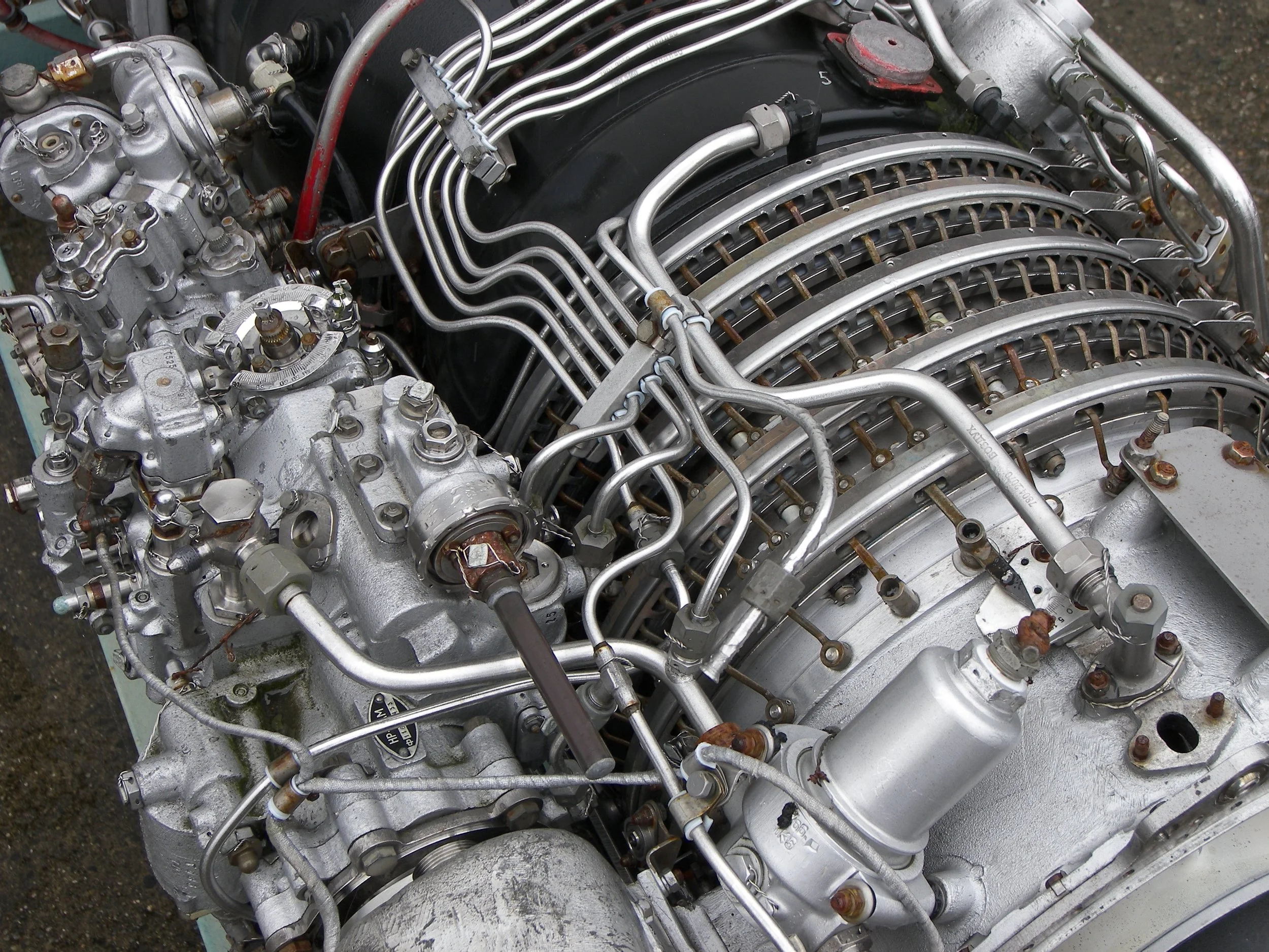 Close-up view of a complex, vintage aircraft engine with numerous metal pipes, valves, and components.
