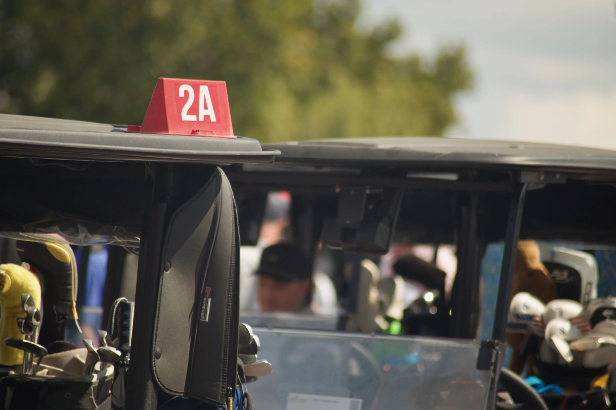 Golf clubs and bags on a golf cart at an outdoor golf course.
