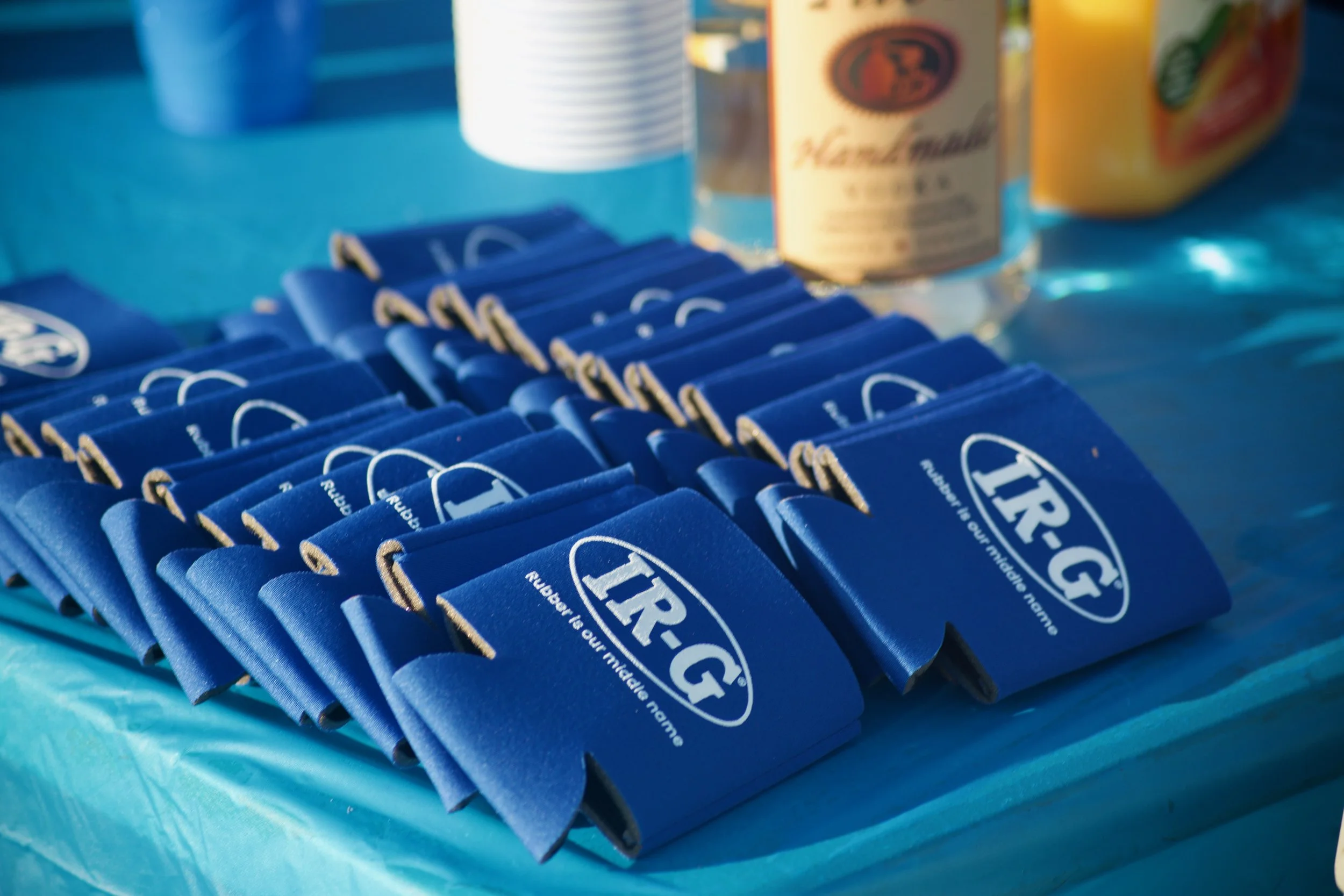 Blue disposable wristbands with white text reading 'HIR'. Several stacked white cups and canned juices are present on a blue surface.