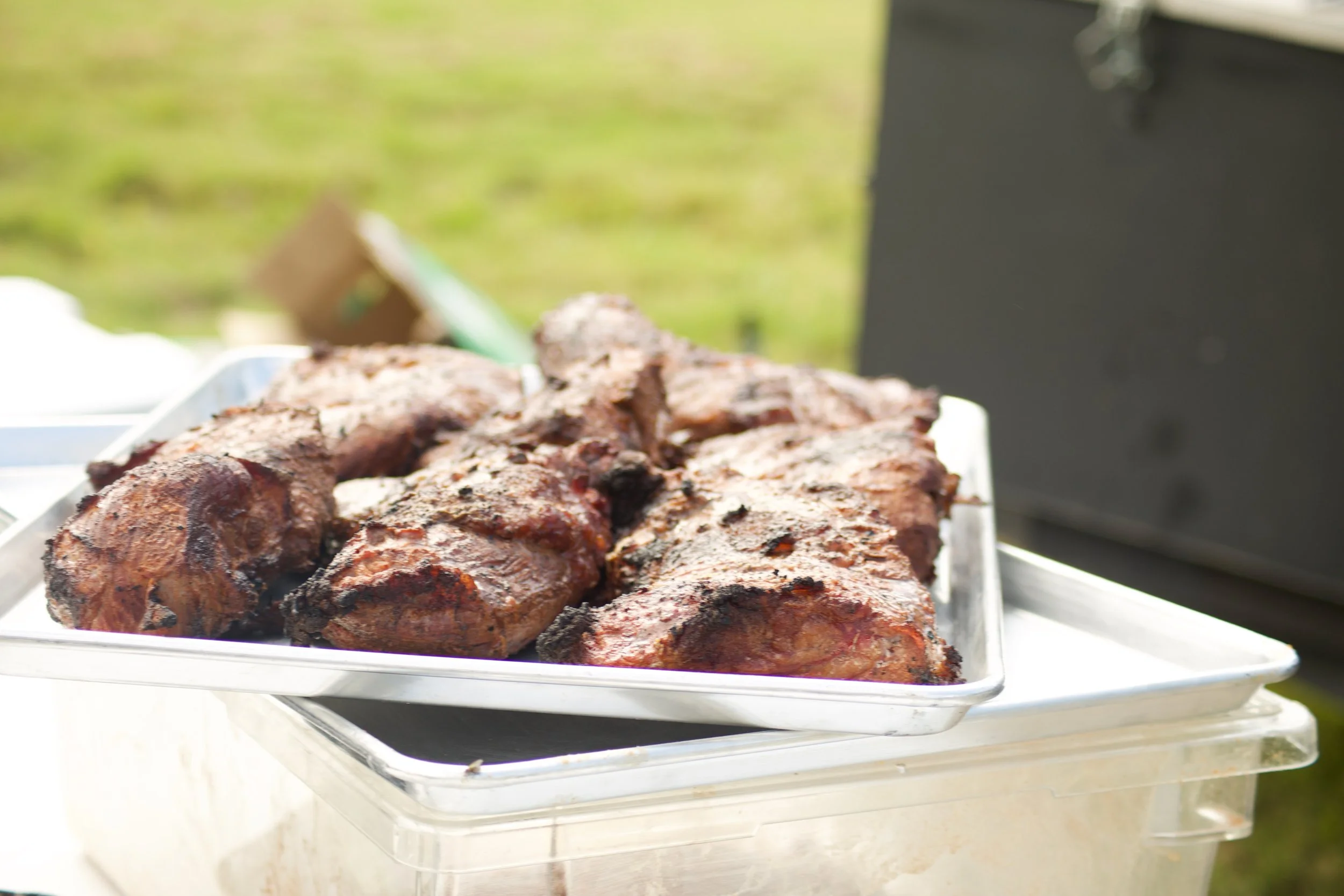 Barbecue ribs on a metal tray outdoors.