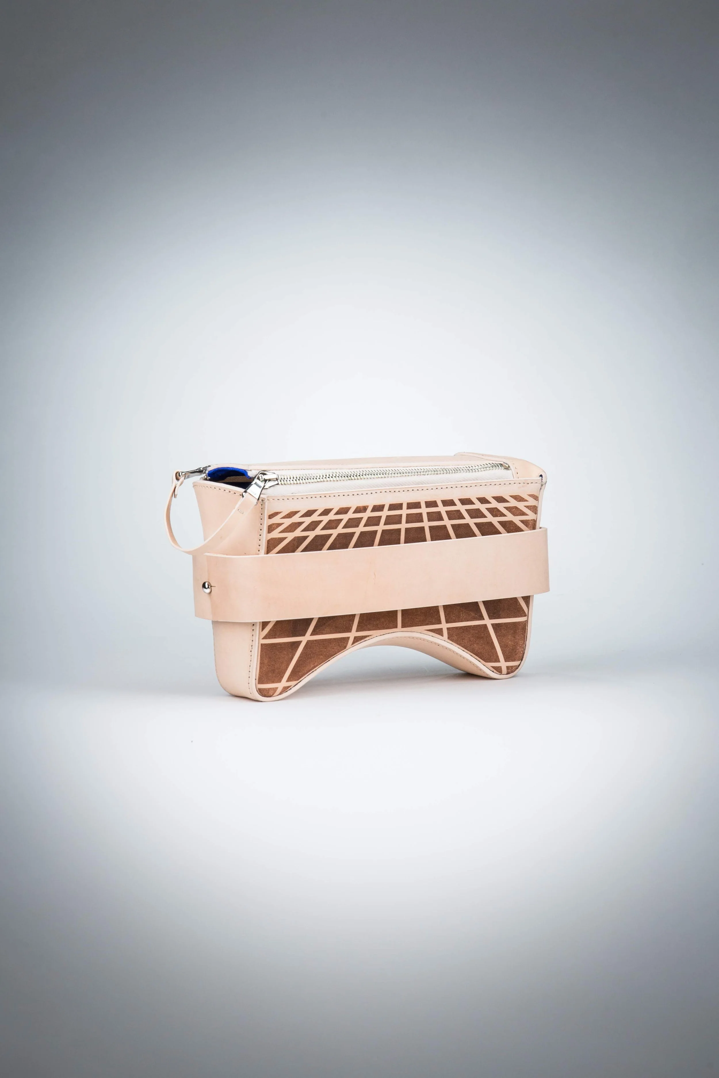 Modern beige handbag with geometric design and zip closure on white background.