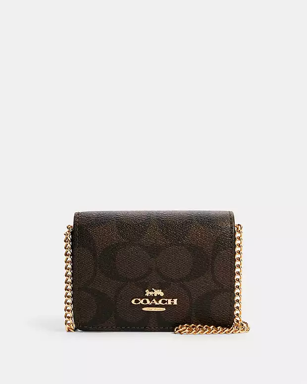 Coach brown signature print crossbody bag with gold chain strap.