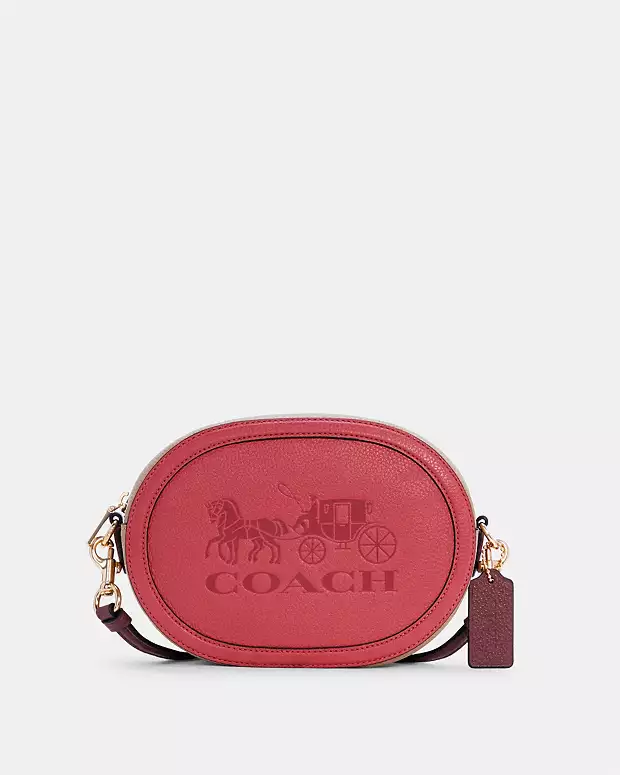 Red oval Coach crossbody bag with embossed horse and carriage logo.