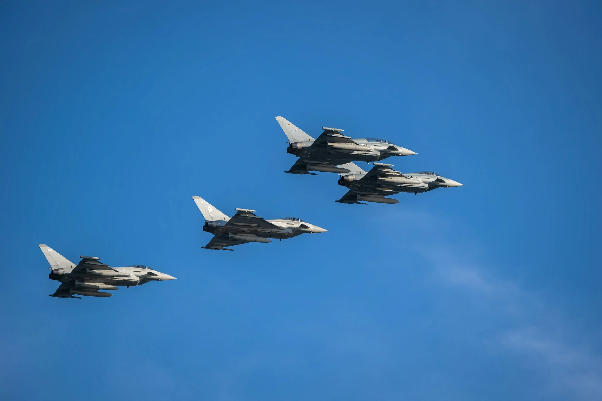 Four fighter jets flying in formation against a blue sky.