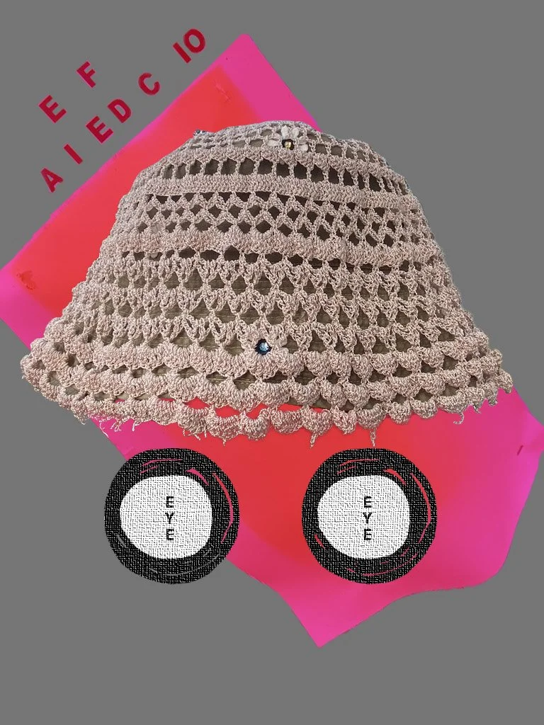 A crocheted beige hat with decorative gems on a pink and gray background. The background features paint swatches labeled from "E" to "F" and two stylized eye icons labeled "EYE."