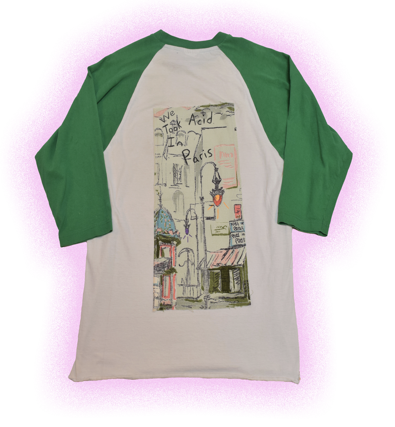 A white and green raglan shirt with a graphic design featuring a city scene, including street signs and buildings, with roughly handwritten words like 'We', 'Took', 'Aid', 'Iraq', 'Paris', and some smaller text.