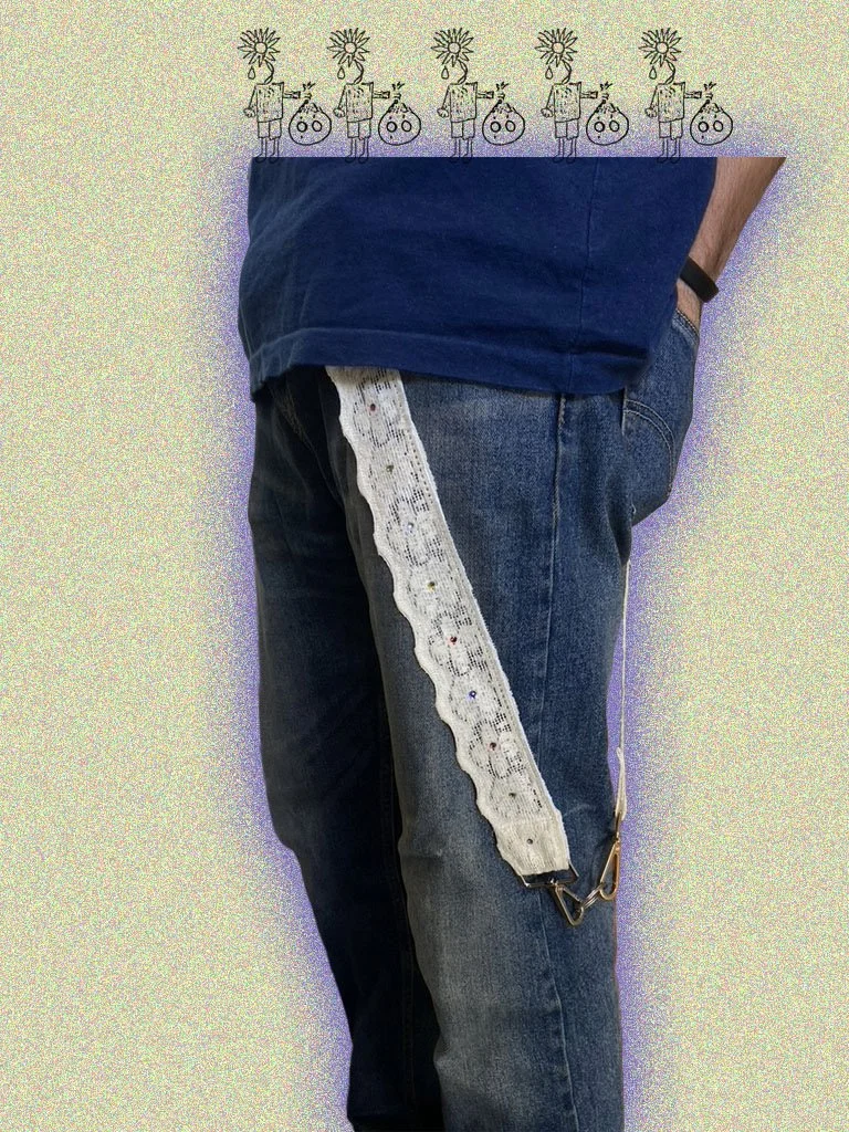 Close-up of a person wearing blue jeans and a navy blue shirt, with a lace trim accessory attached to the belt loop on the right side.