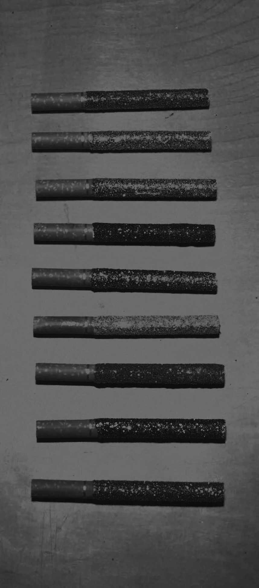 Black cigarettes arranged in two columns on a wooden surface.