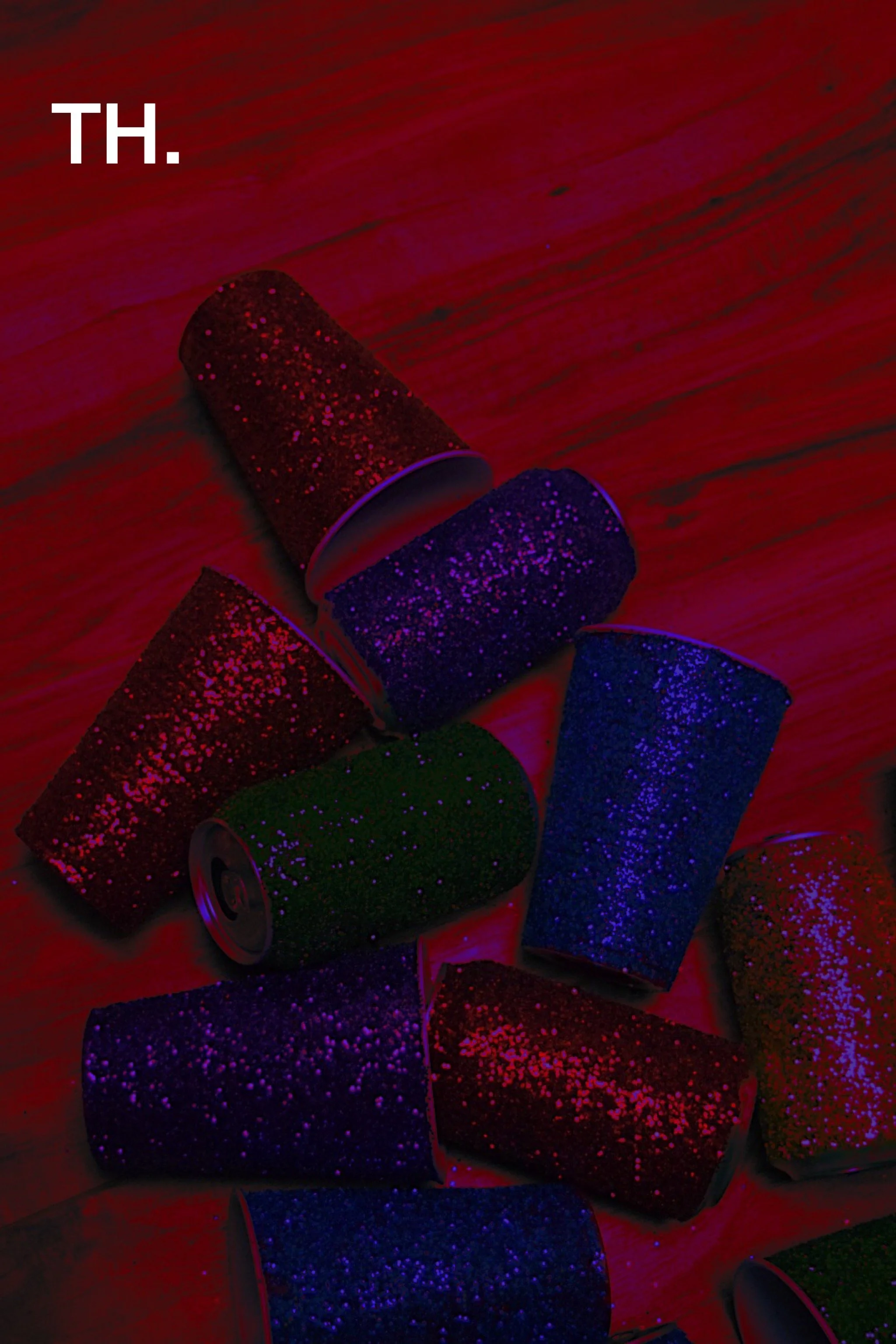 Colorful spray paint cans on a wooden surface illuminated with ultraviolet light.