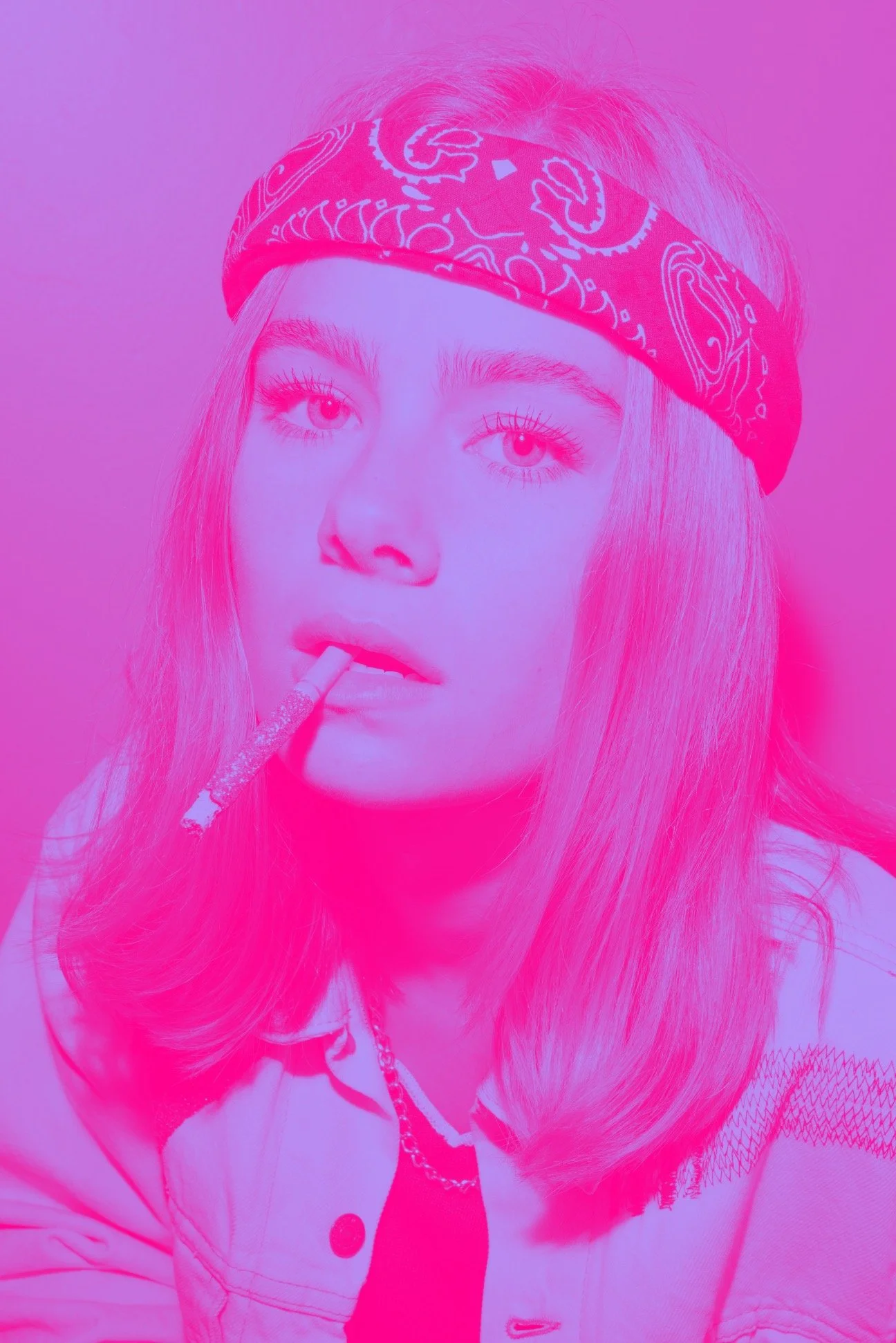 A young woman with long hair wearing a bandana and a chain necklace, looking at the camera with a cigarette in her mouth.
