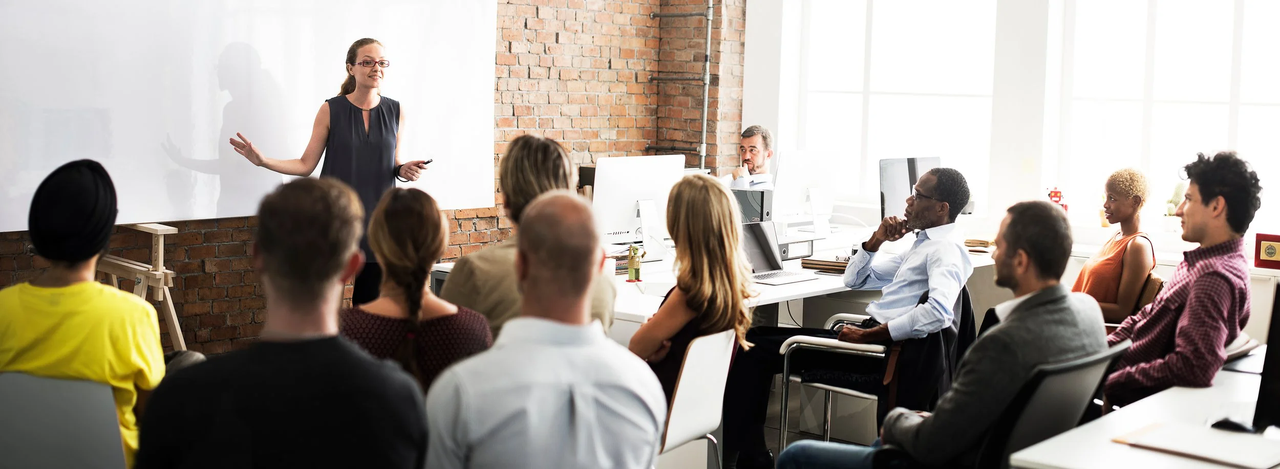 Business professionals in a circle discussing and clapping in a large office space.