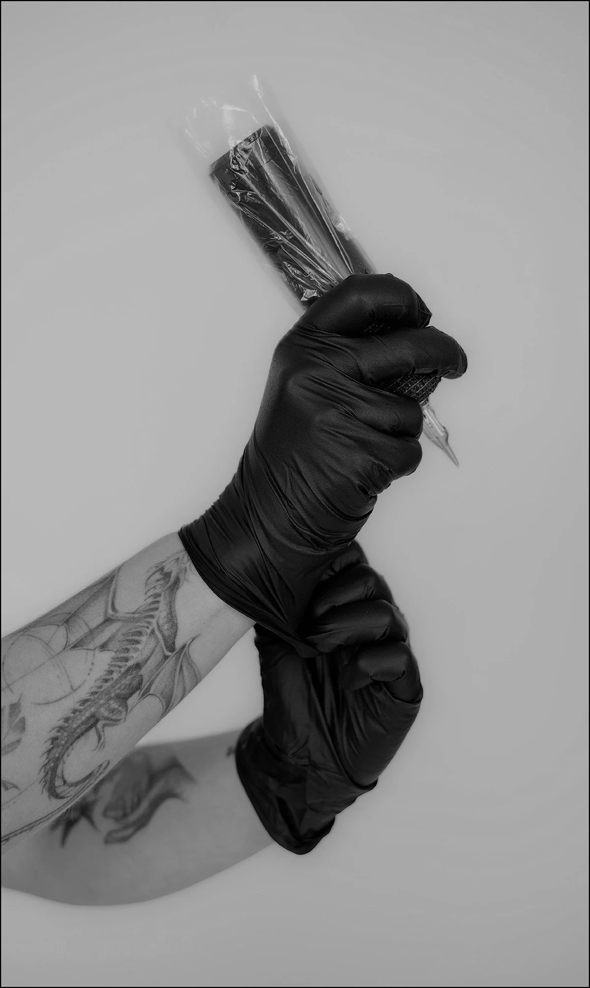 Closeup of tattoo artist wearing gloves holding tattoo gun.