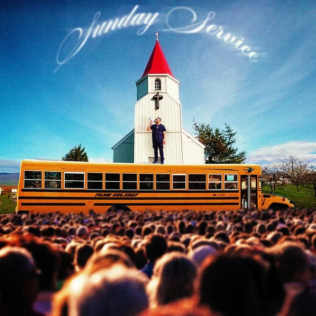  Fame Holiday standing on top of a yellow school bus in front of a church with a red steeple. He's holding a microphone and there is a large crowd of people in the foreground. The sky is blue, and the words "Sunday Service" are written in the sky.
