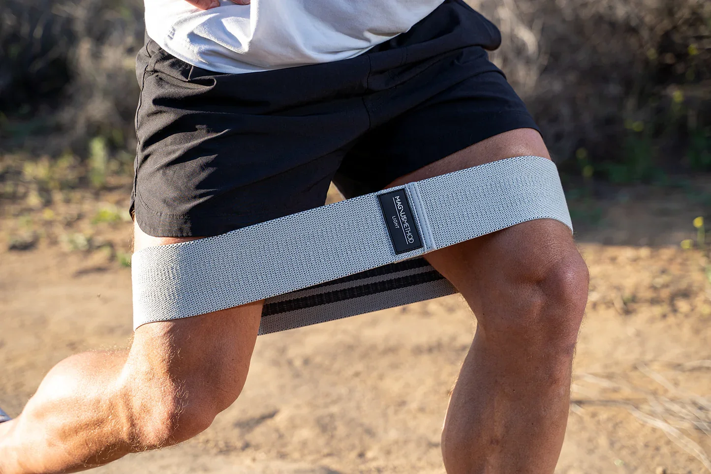 Close-up of a man's upper leg and knee with a knee brace on his right knee during outdoor activity.