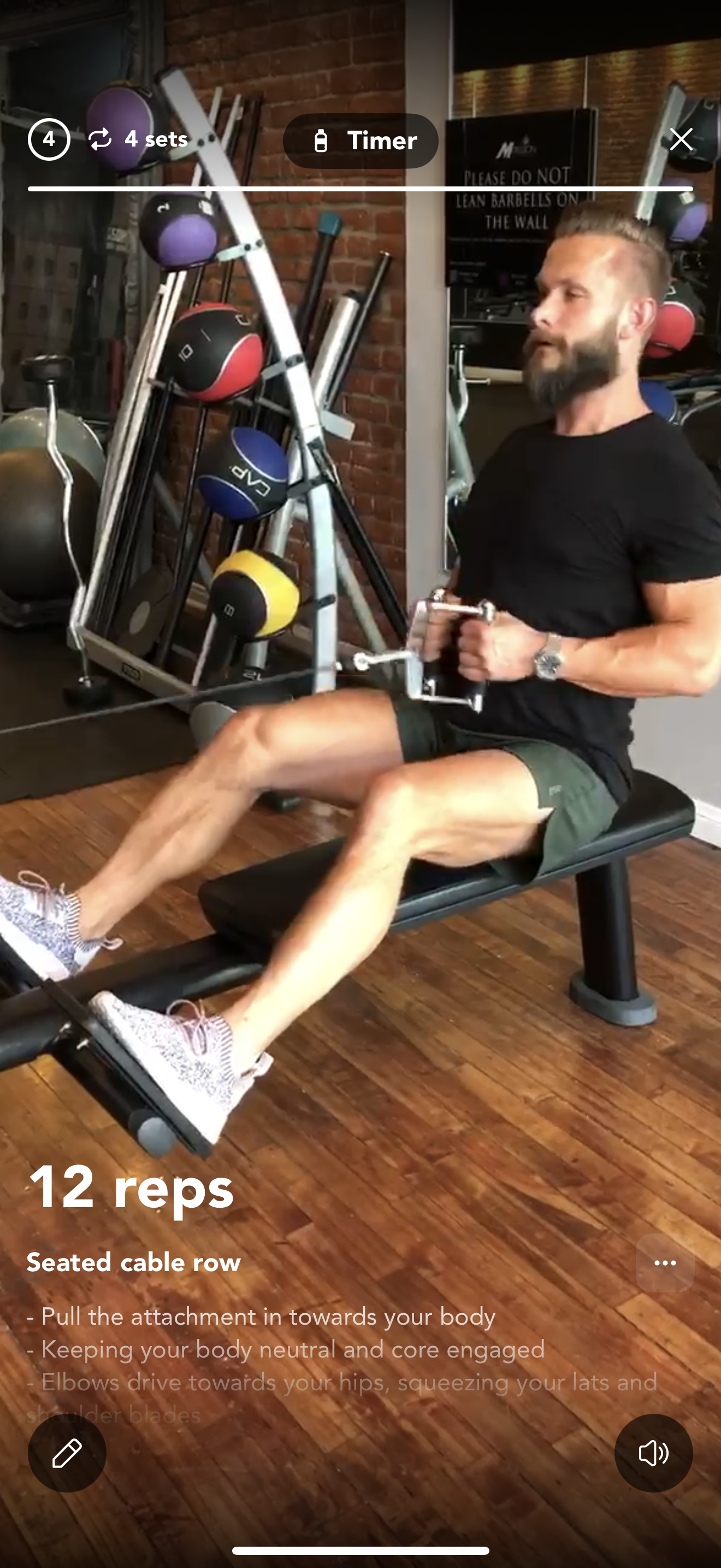 Person doing a bear crawl exercise on a gym floor with equipment in the background.