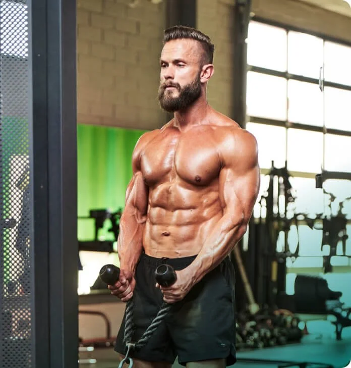 Muscular man exercising with ropes in gym.