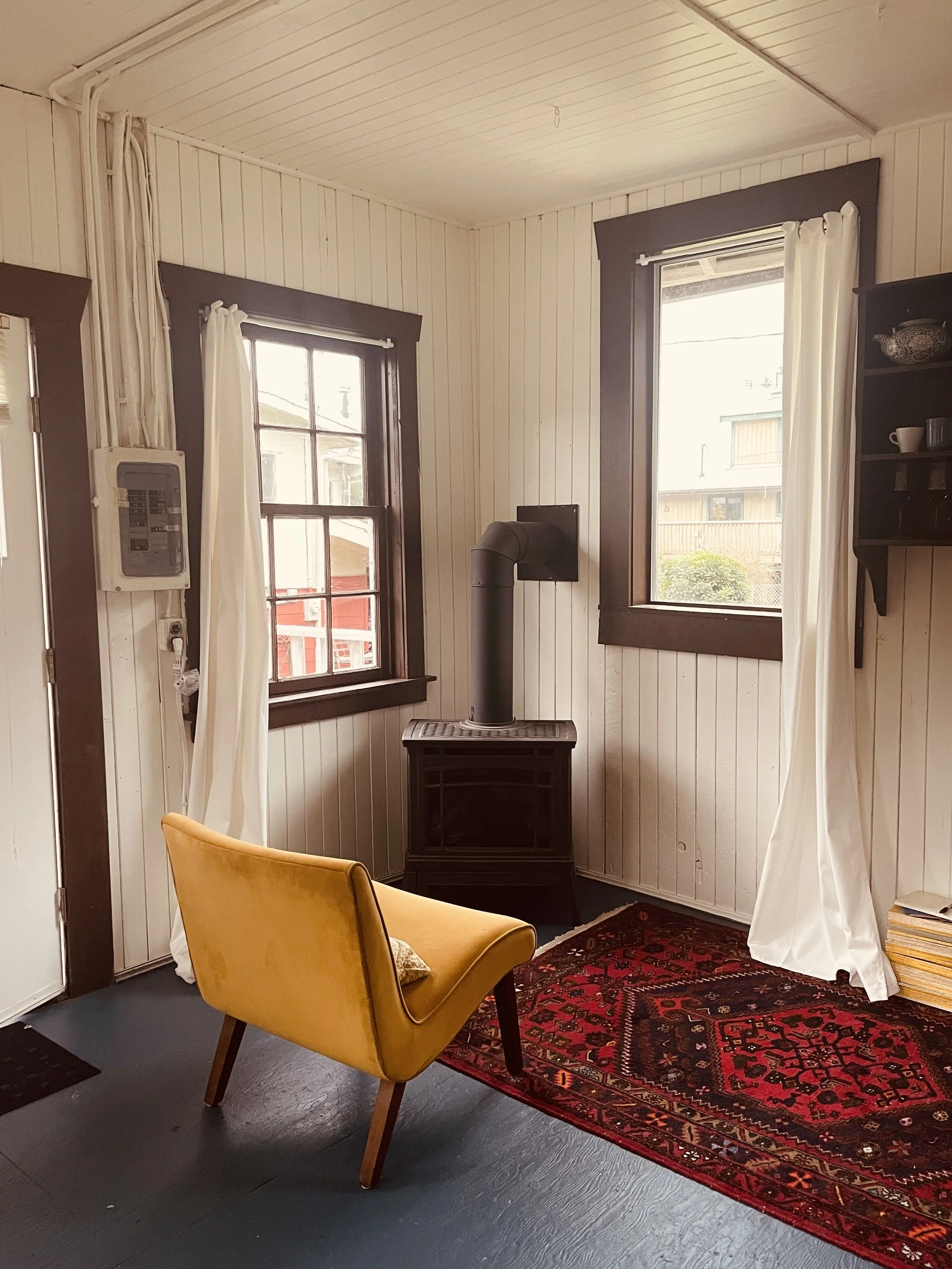 seating area view of the fireplace, windows facing the ocean; main house to the right (west) 