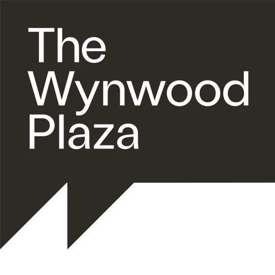 Black and white sign with text reading "The Wynwood Plaza".