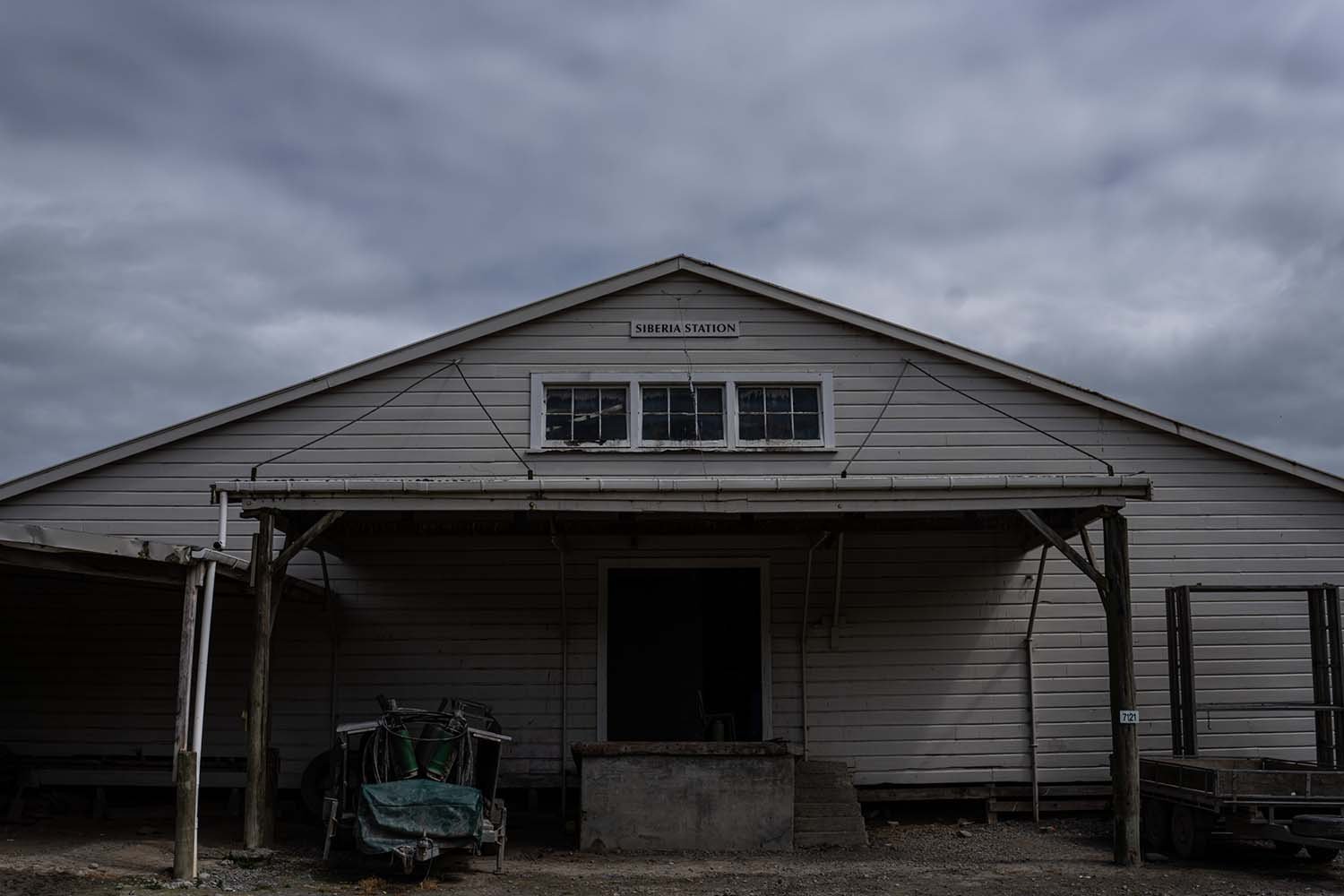 Front view of a wooden warehouse building with a sign reading 'Siberia Station' under a cloudy sky.