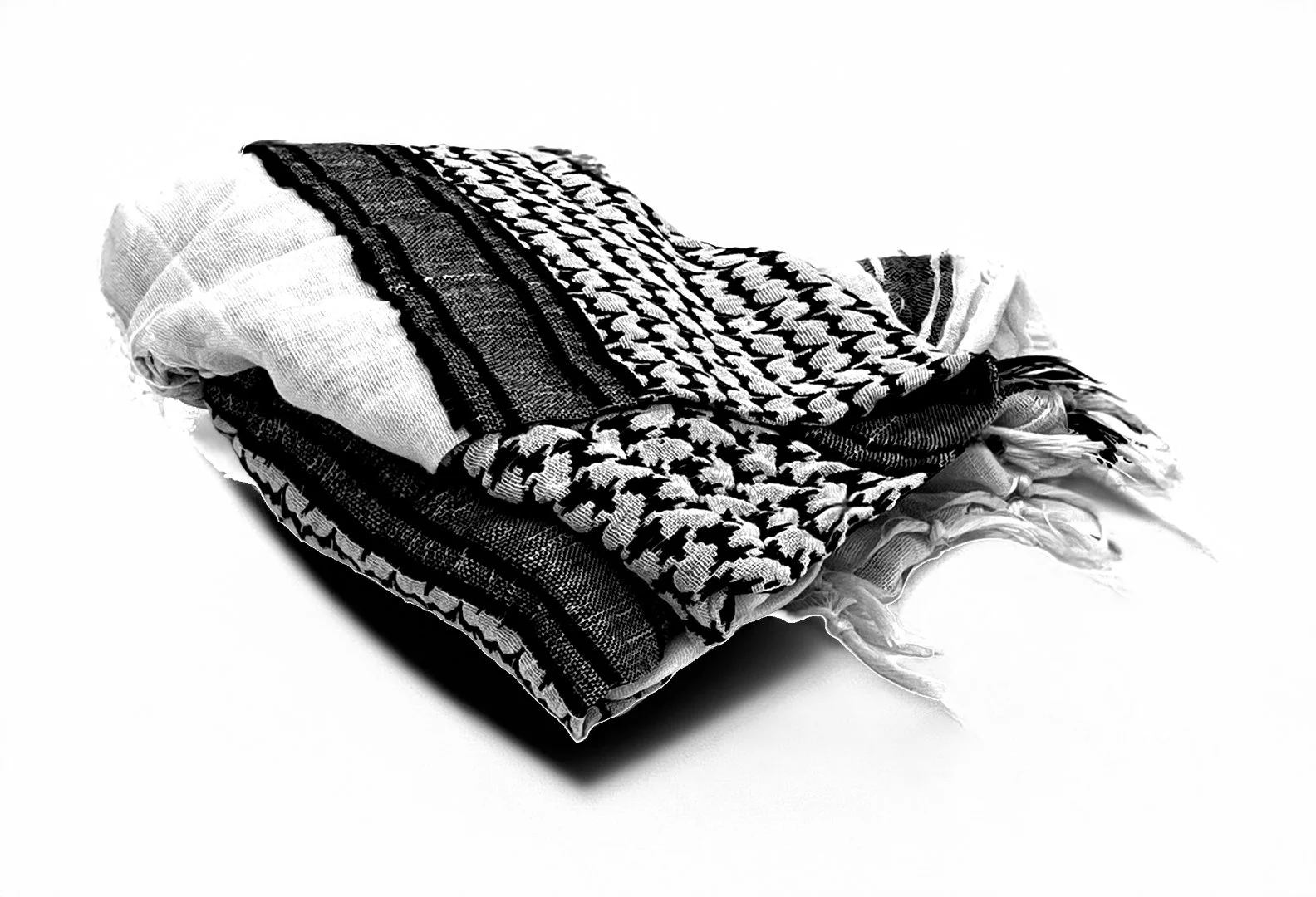 Picture of a black and white keffiyeh (Palestinian garment/scarf) folded on a table