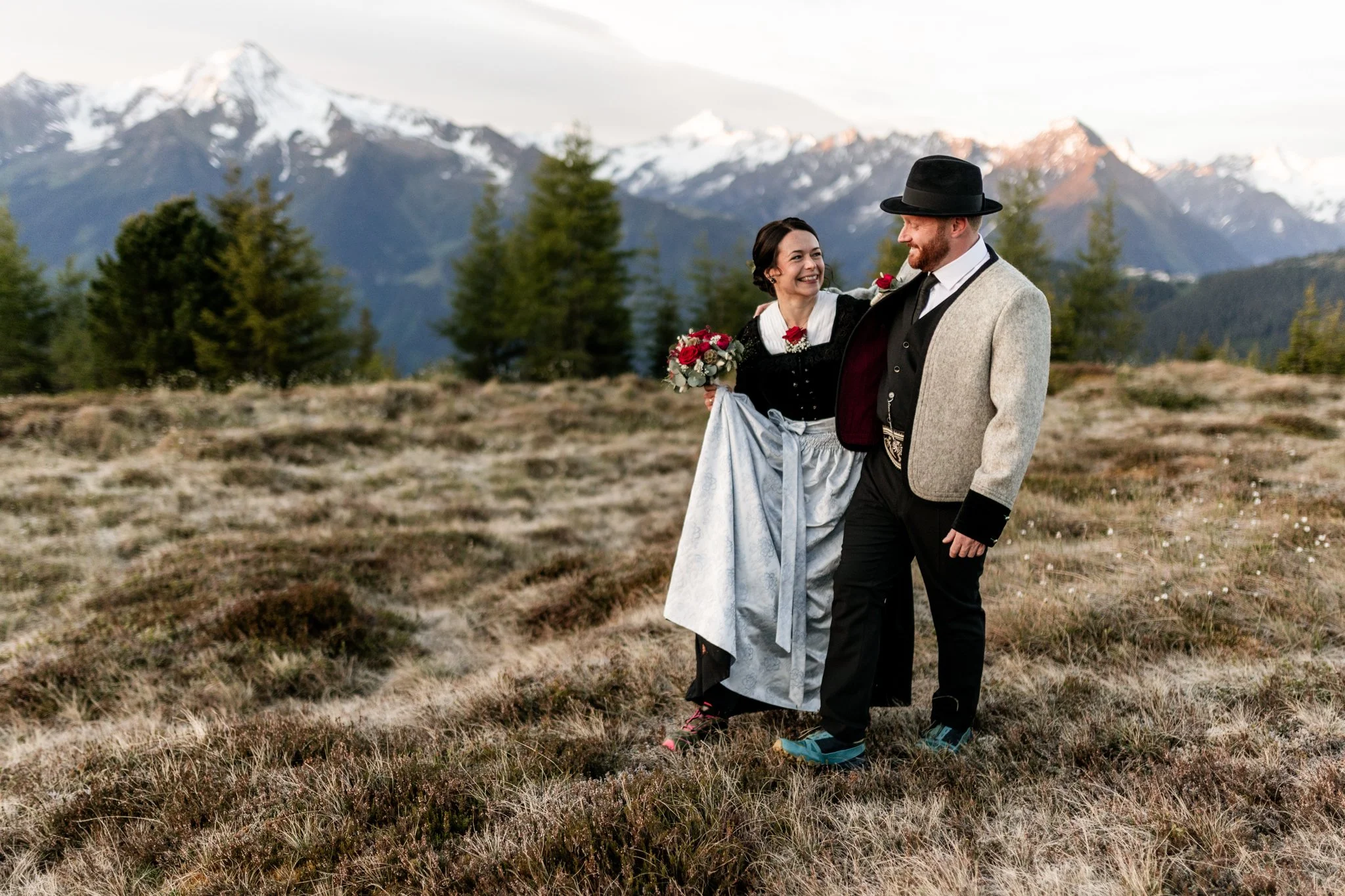 Frau blickt Mann lachend an und ist ganz verliebt. Hochzeit am Berg in Tirol. Fotoshooting bei Sonnenaufgang.