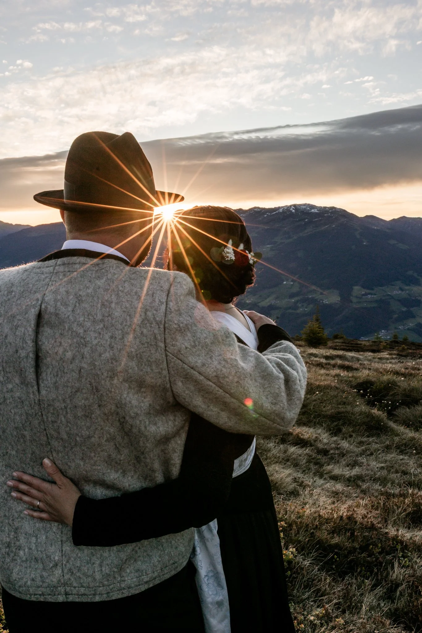 Mann und Frau umarmen sich, die Sonne scheint das erste Mal über die Bergkette im Osten. Die ersten Sonnenstrahlen wärmen das Brautpaar, welches sich in den Zillertaler Alpen, bei Mayrhofen befindet. 