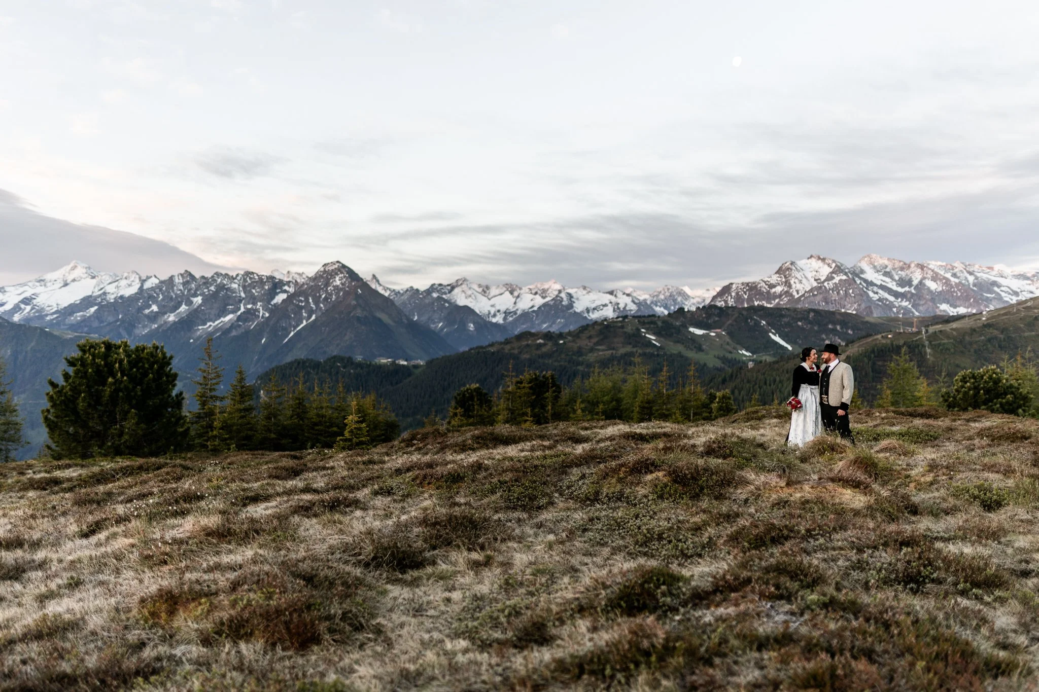 Paar küsst sich im Vordergrund, im Hintergrund umringt von den Bergen des Zillertales, Olperer in Hintertux Schlegeis, Zygmondysptize Ginzling, Tristner und Ahornspitze in Mayrhofen