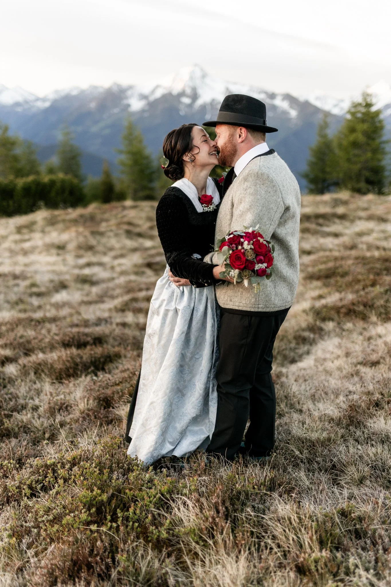 Frau und Mann halten sich gegenseitig fest, küssen sich verliebt - im Hintergrund die Ahornspitze mit Karl-von-Edel-Hütte bei Mayrhofen im Zillertal. Hochzeitsfotografie am Berg.