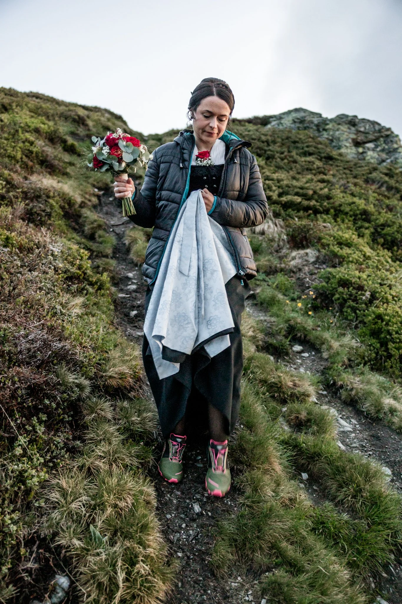 Braut in Tracht beim Zustieg zur Fotolocation am Berg 