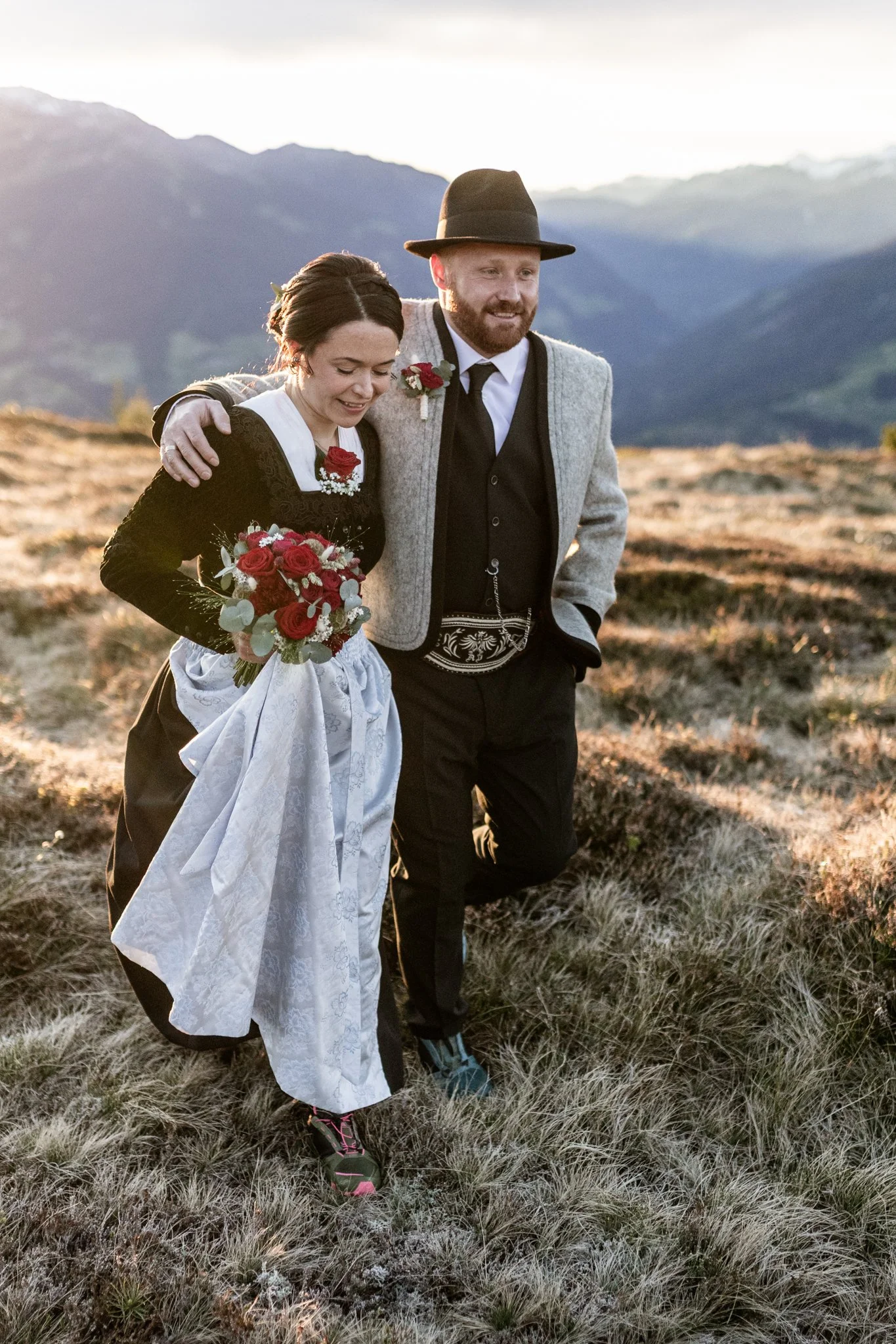 Mann hat seinen rechten Arm über die Schultern der Frau gelegt und führt sie über die Bergwiese im Zillertal. 