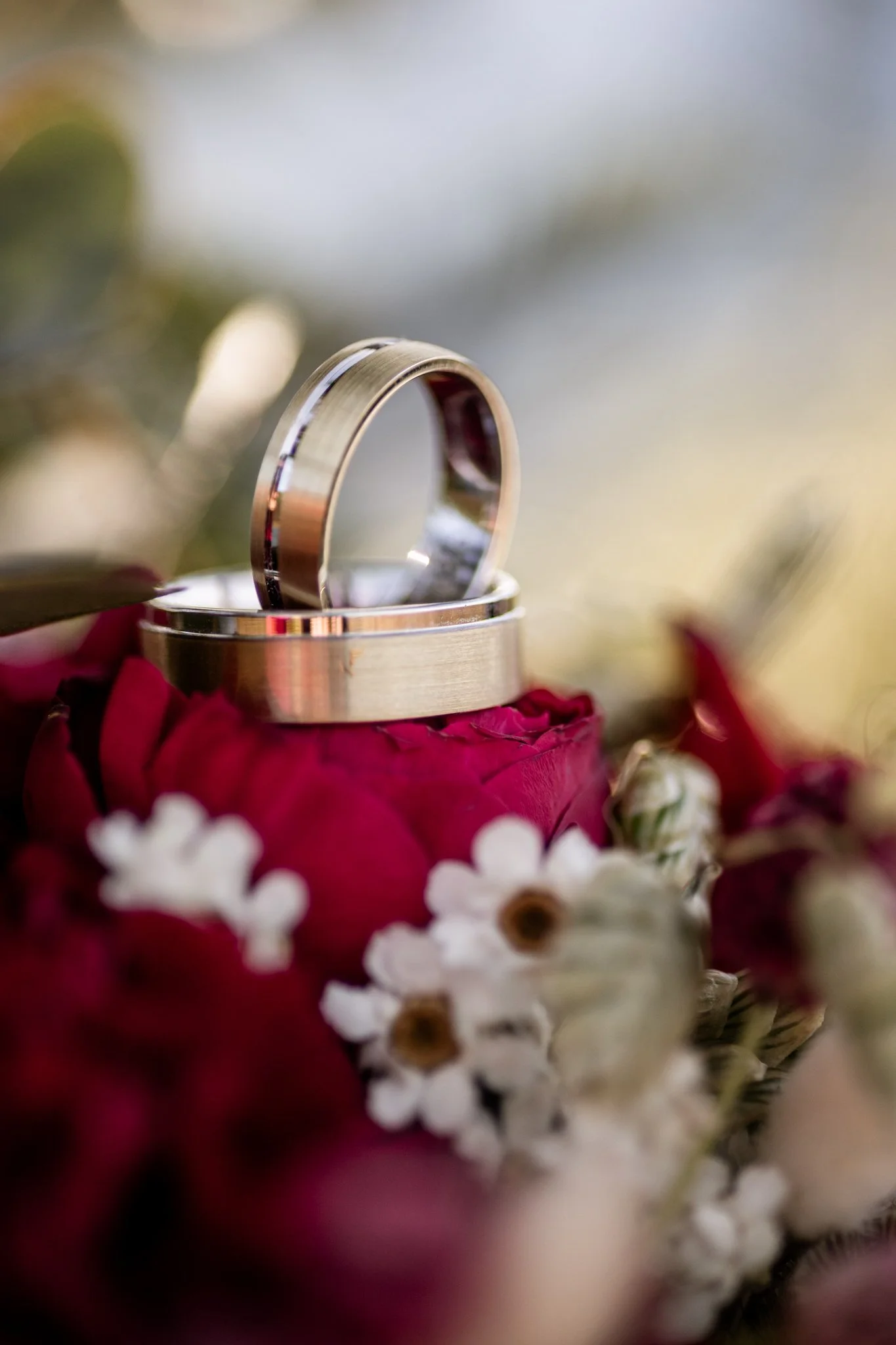 Hochzeitsringe in Gold, mit Brautstrauß mit roten Rosen - Detailfotos einer Hochzeit 