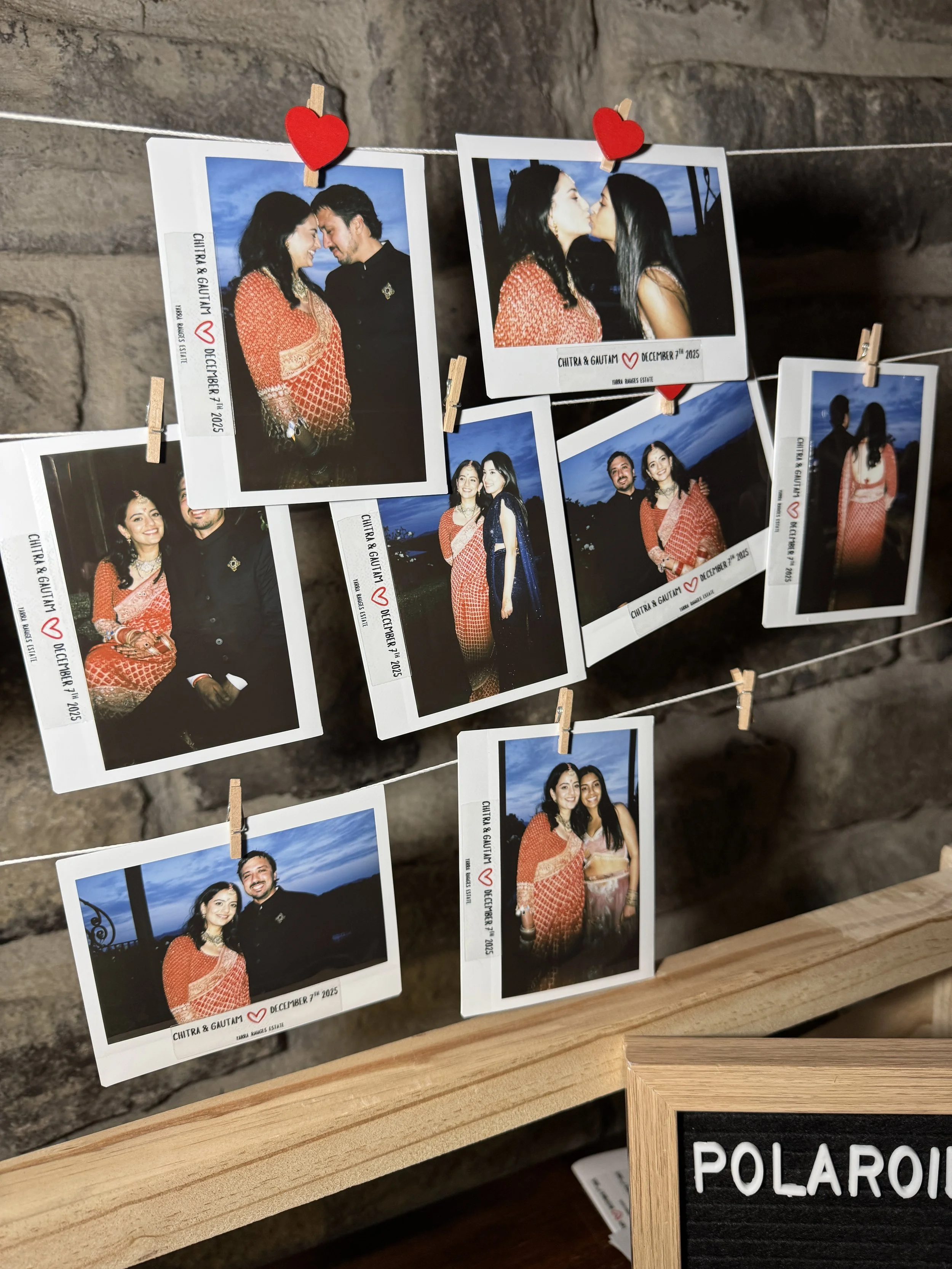 A display of several instant photographs hanging on a string with small clothespins, capturing a couple's outdoor celebration. The photos show the couple in traditional attire, posing, kissing, and together at sunset or nighttime. The background of t