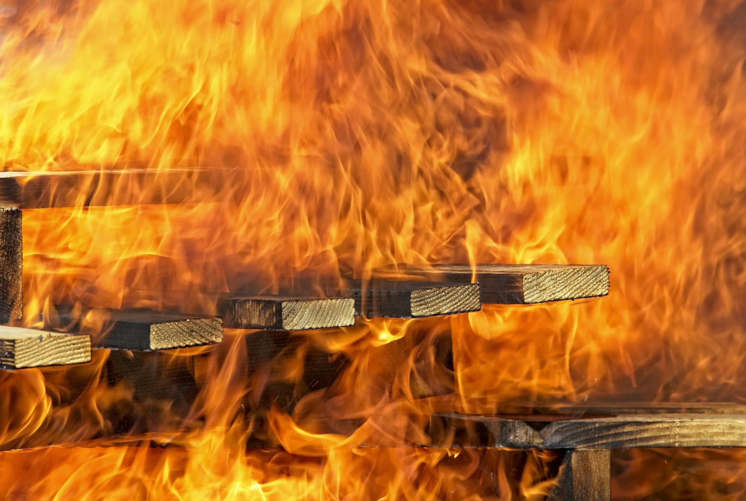 Wooden pallets on fire with bright orange flames.