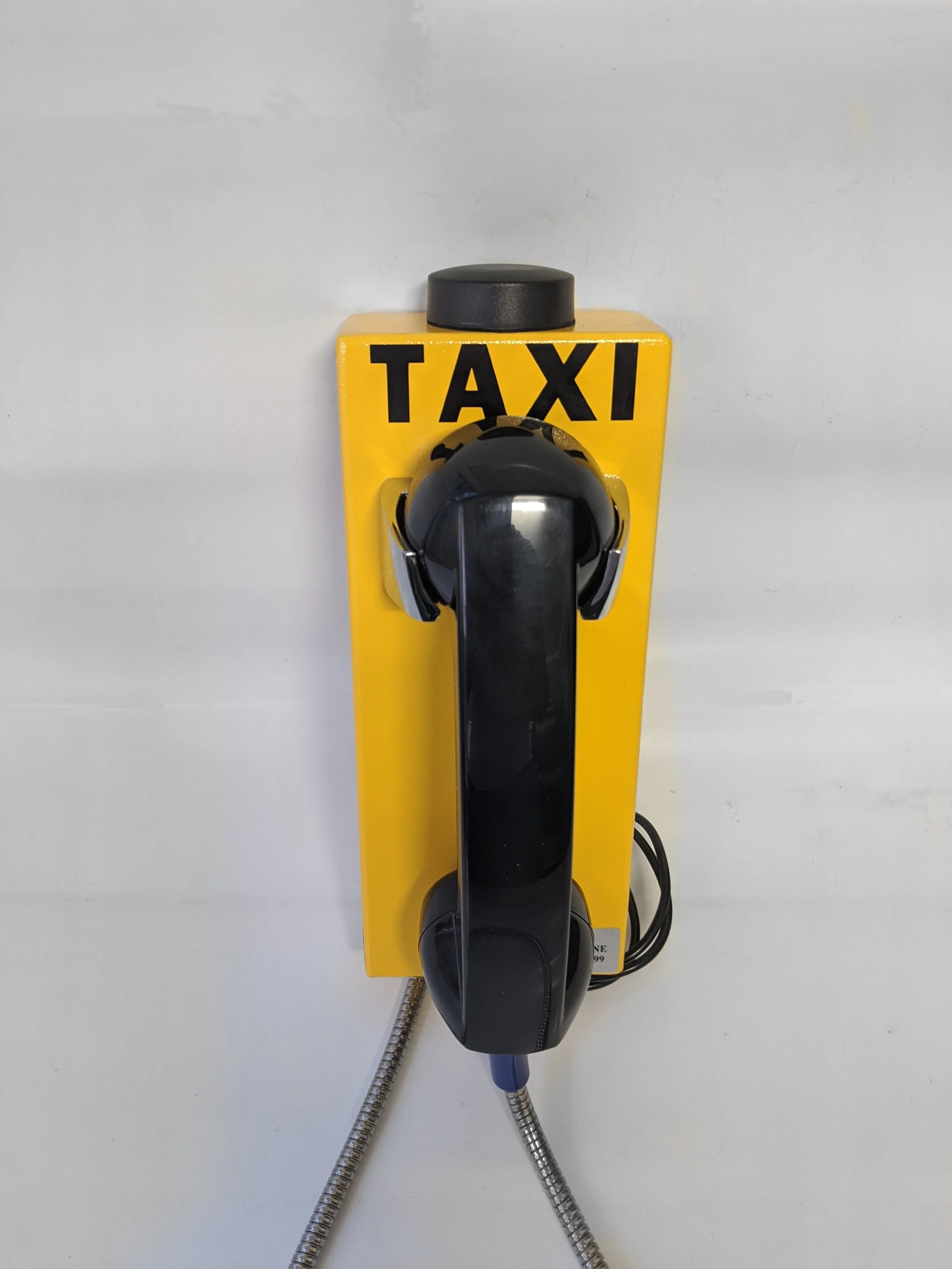 Yellow lift to call taxi phone with black handset and metal cord