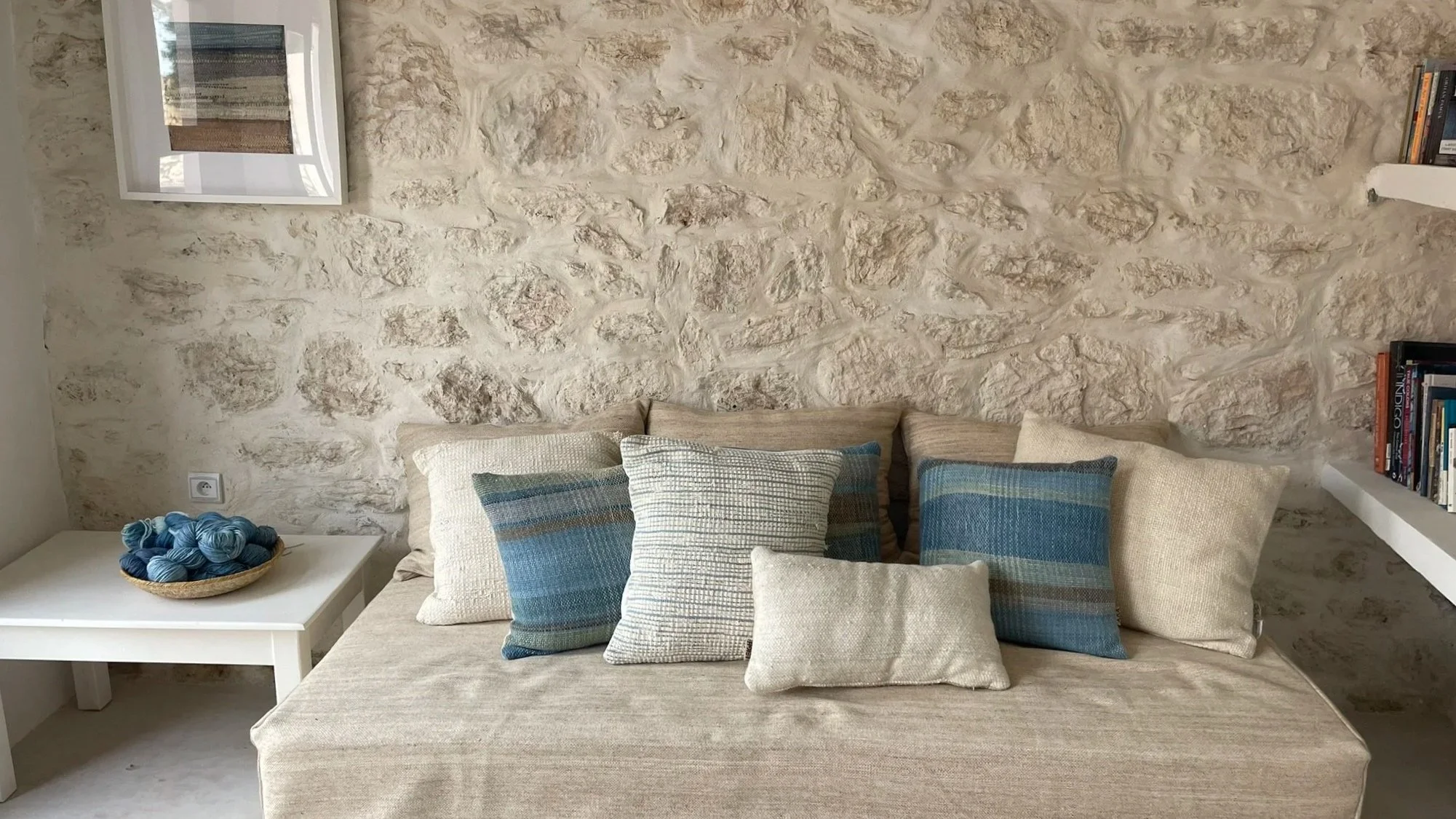 Daybed with handwoven cushions in studio with stone wall feature