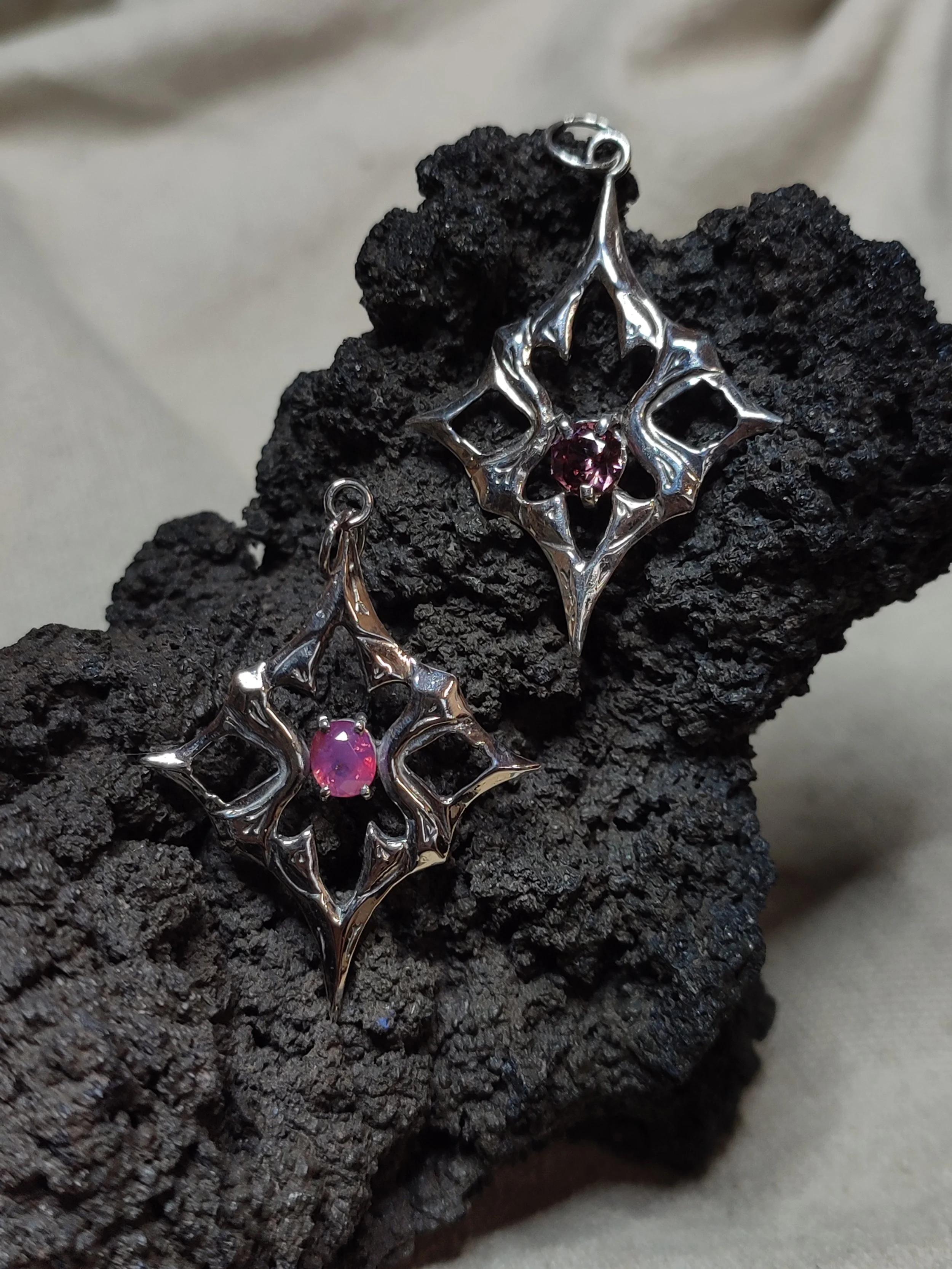 Deux pendentifs Shrine en argent massif 925 avec des pierres précieuses, exemples de déclinaisons sur mesure des créations uniques de WIT joaillerie posées sur une roche noire.