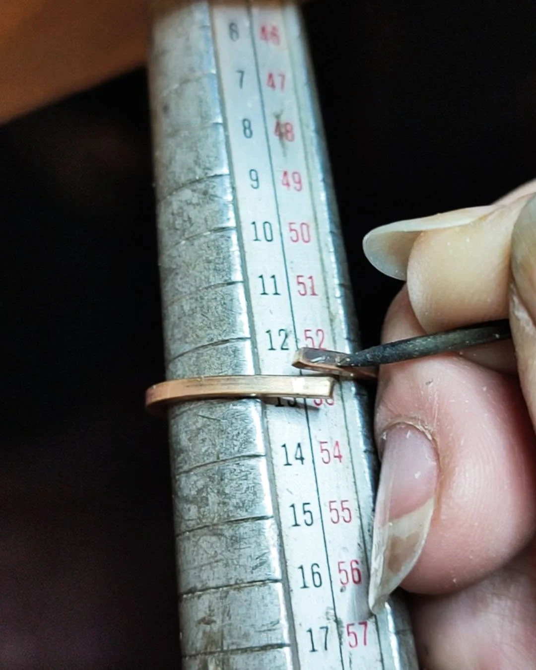 La joaillère utilise un outil pour ajuster une bague en or sur un facteur de mesure métallique.