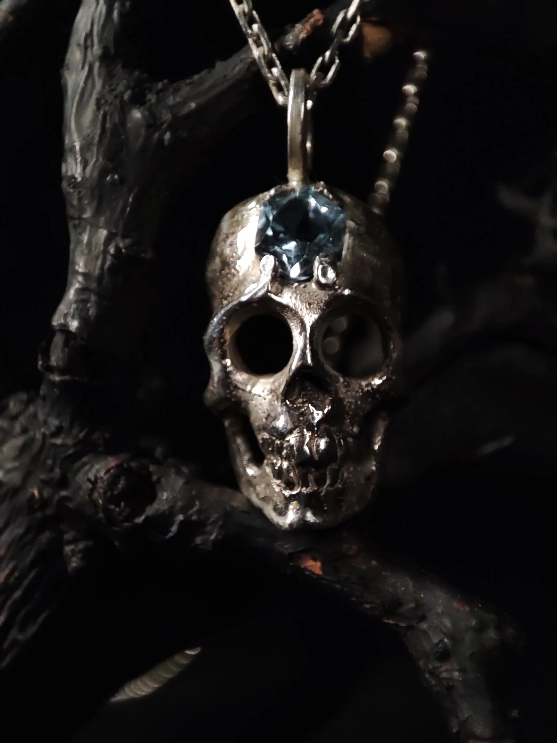 Pendentif crane en argent massif surmonté sur son front d'une aigue marine représentant la tete de mort d'un saint des catacombes de Paris. Memento mori inspiration gothique, bijou victorien