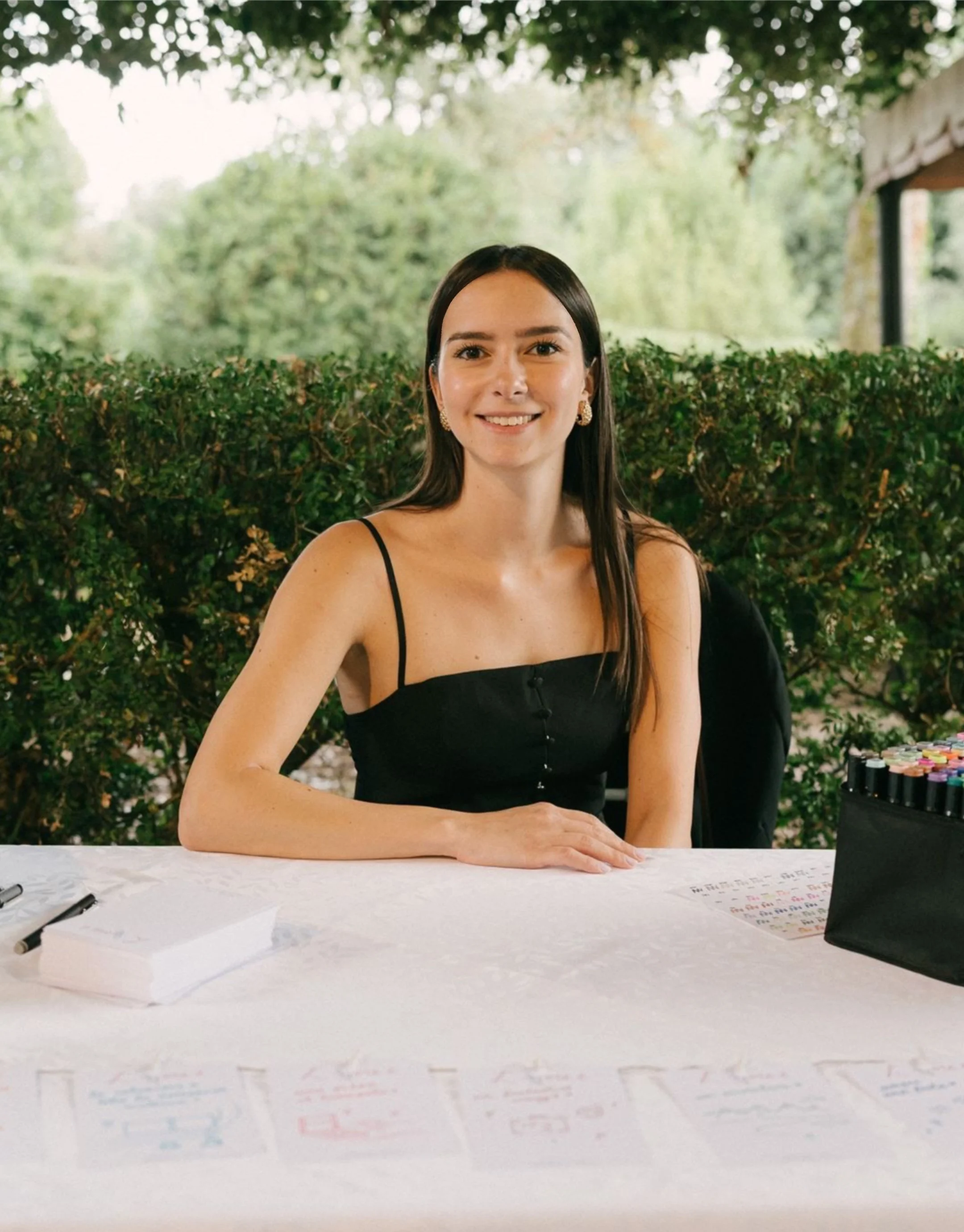 Live sketching: tavolo con un set di pennarelli colorati, un quadro con scritte in italiano e disegni, e alcune schede con poesie o messaggi scritti in italiano, decorato con un tema romantico e floreale.