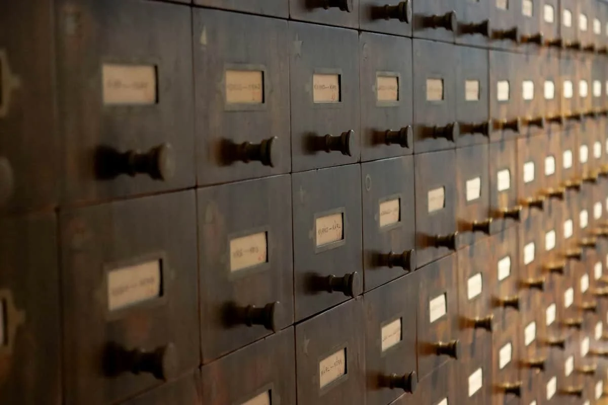 Nahaufnahme einer alten Holzkartei mit vielen Schubladen und handbeschrifteten Etiketten.