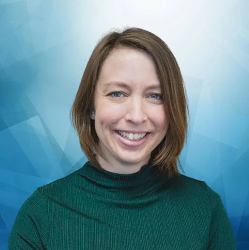 Porträt einer lächelnden Frau mit braunen, schulterlangen Haaren vor einem blauen geometrischen Hintergrund.