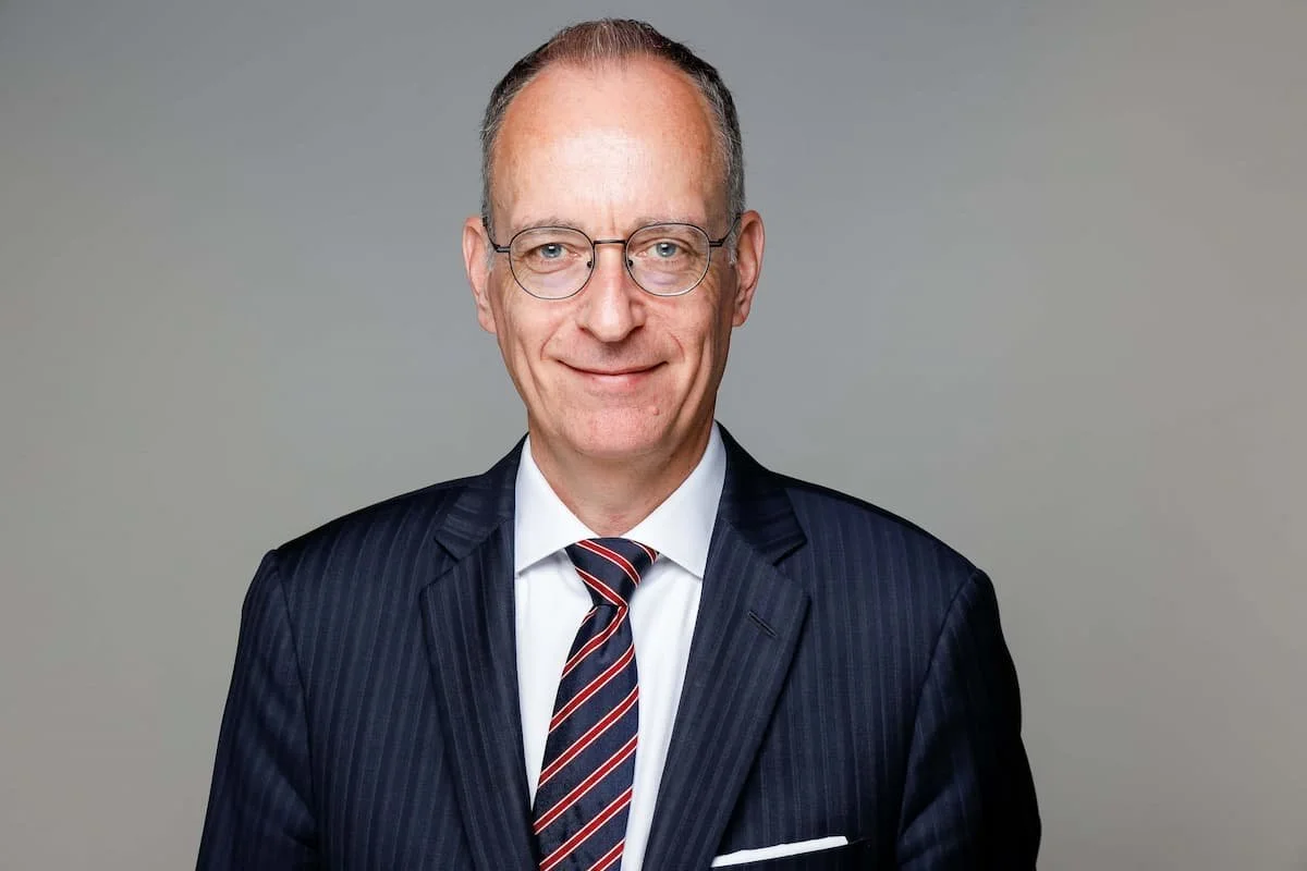 Mann in dunkelblauem Anzug mit Brille und gestreifter Krawatte