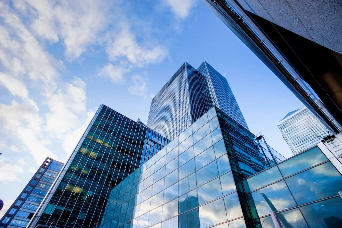 Moderne Bürohochhäuser mit Glasfassaden aus der Froschperspektive vor blauem Himmel mit Wolken.