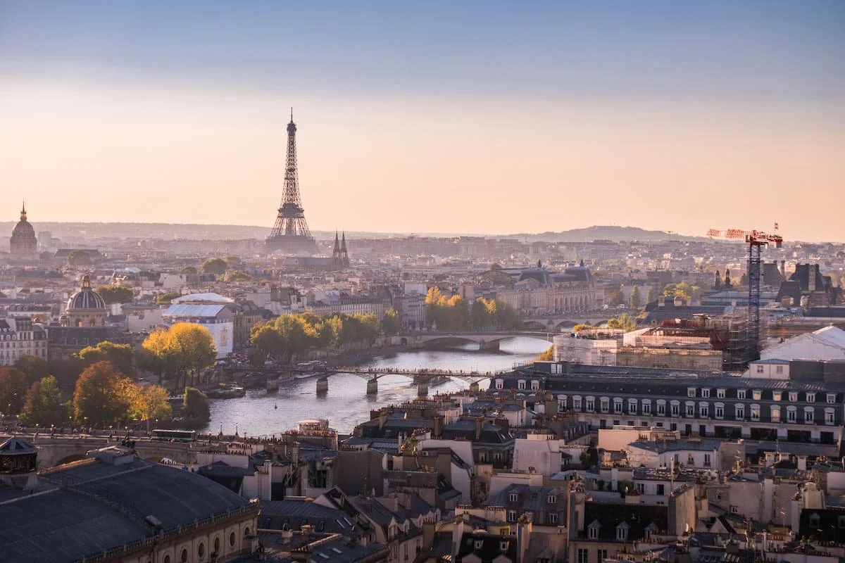 Panoramablick auf Paris mit Eiffelturm, Seine-Fluss, Brücken und Stadtarchitektur bei Sonnenuntergang.