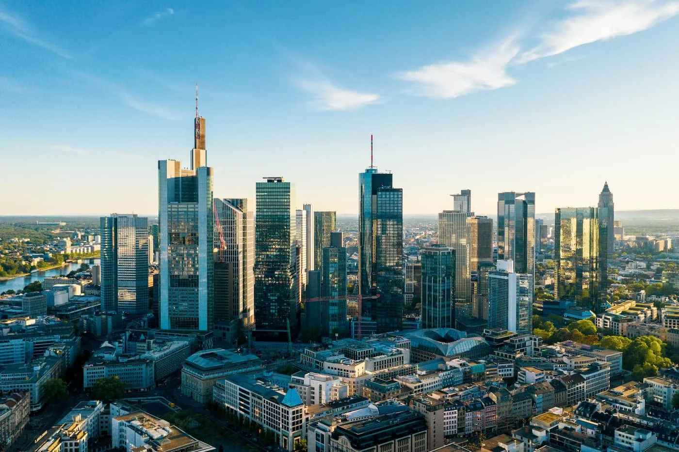 Hochhaus Stadtbild mit Wolkenkratzern, blauer Himmel und Wasser im Hintergrund, Sonnenlicht reflektierende Glasfassaden.
