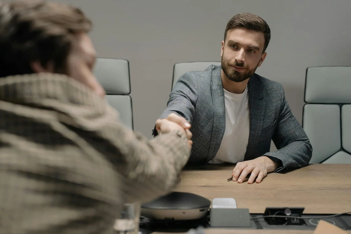 Nahaufnahme von zwei Männern, die sich die Hand in einem Konferenzraum schütteln