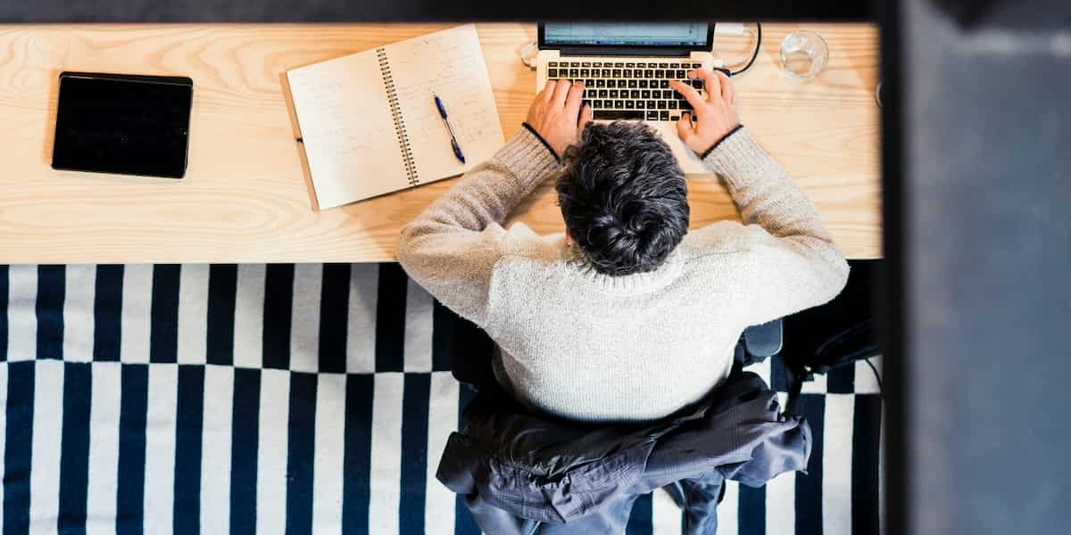 Vogelperspektive auf einen Büroangestellten, der am Laptop sitzt